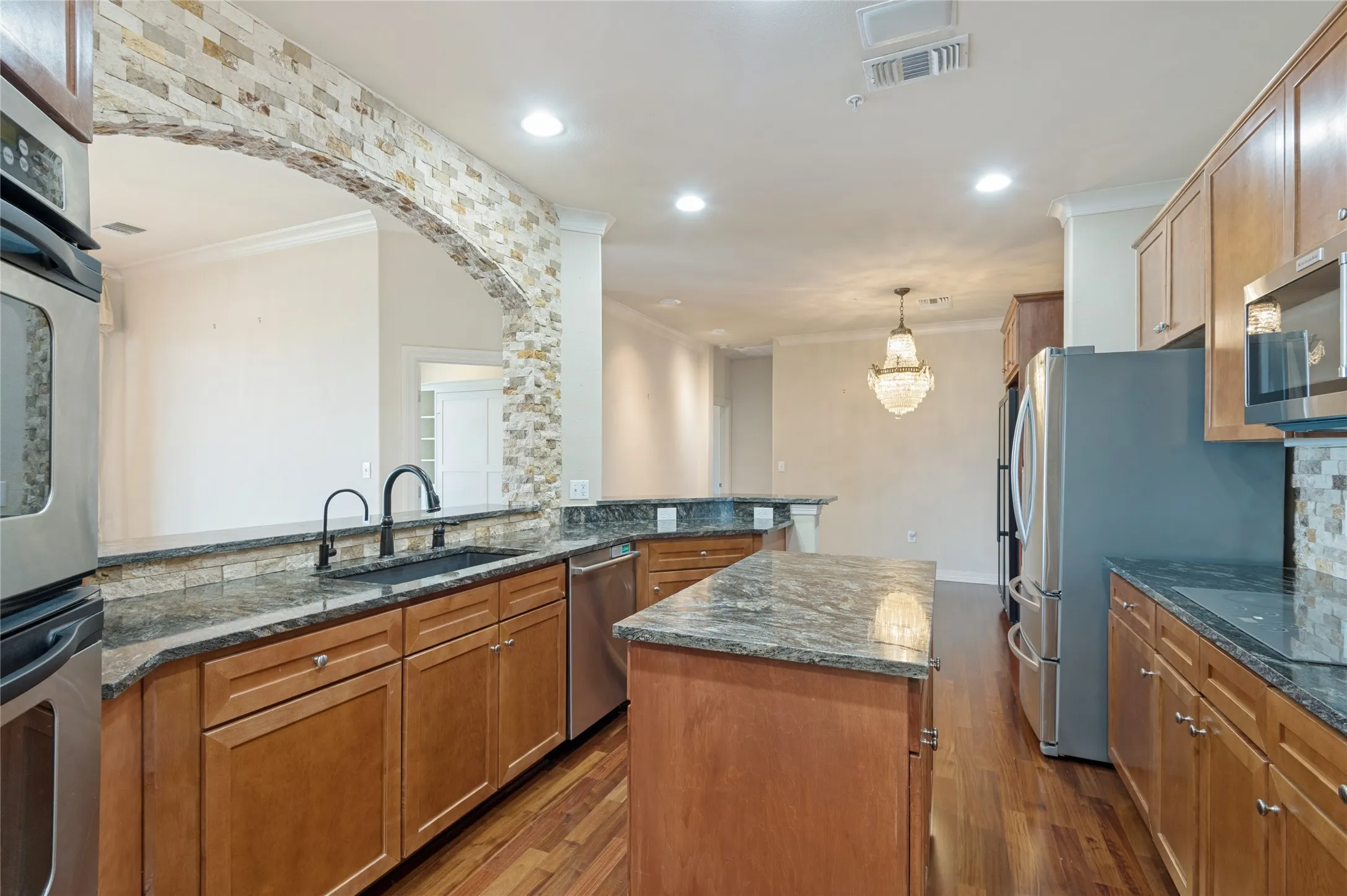 Gourmet kitchen featuring wood-finish flooring, granite countertops, mobile island, and light Shaker-style wood cabinetry
