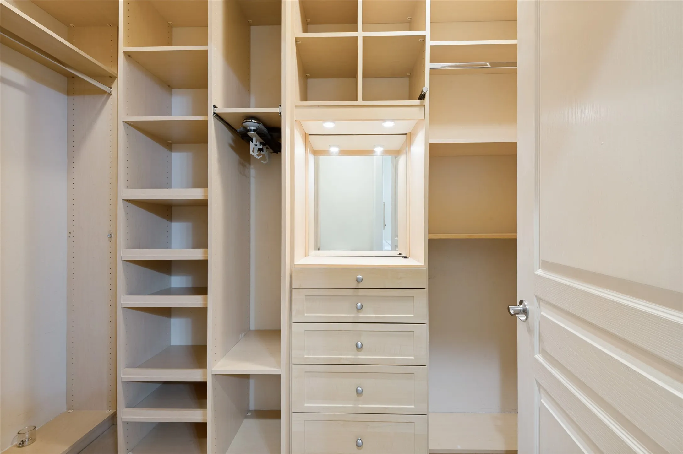 Custom closet system featuring light wood-finish cabinetry, integrated shelving, and multiple drawers with brushed nickel hardware