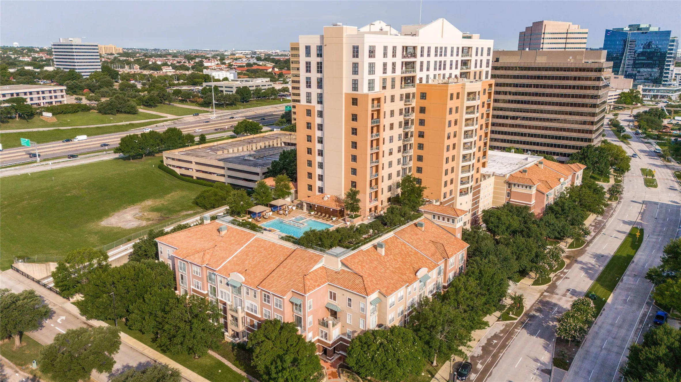 Multi-story residential complex featuring a rooftop swimming pool , barbecue area and surrounding green spaces