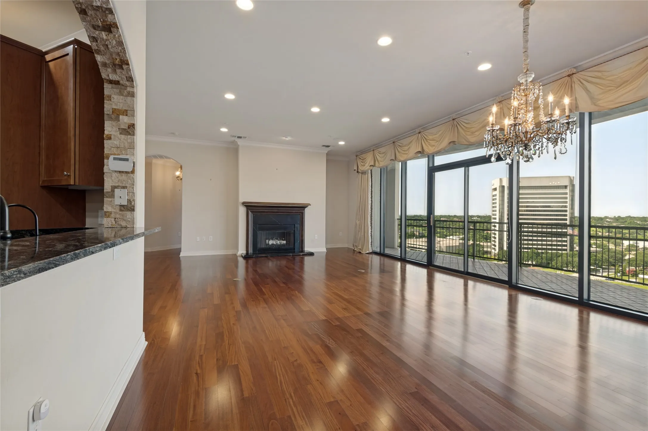Open floor plan with gleaming wood floors, luxurious chandeliers, wood burning fireplace, and sweeping views