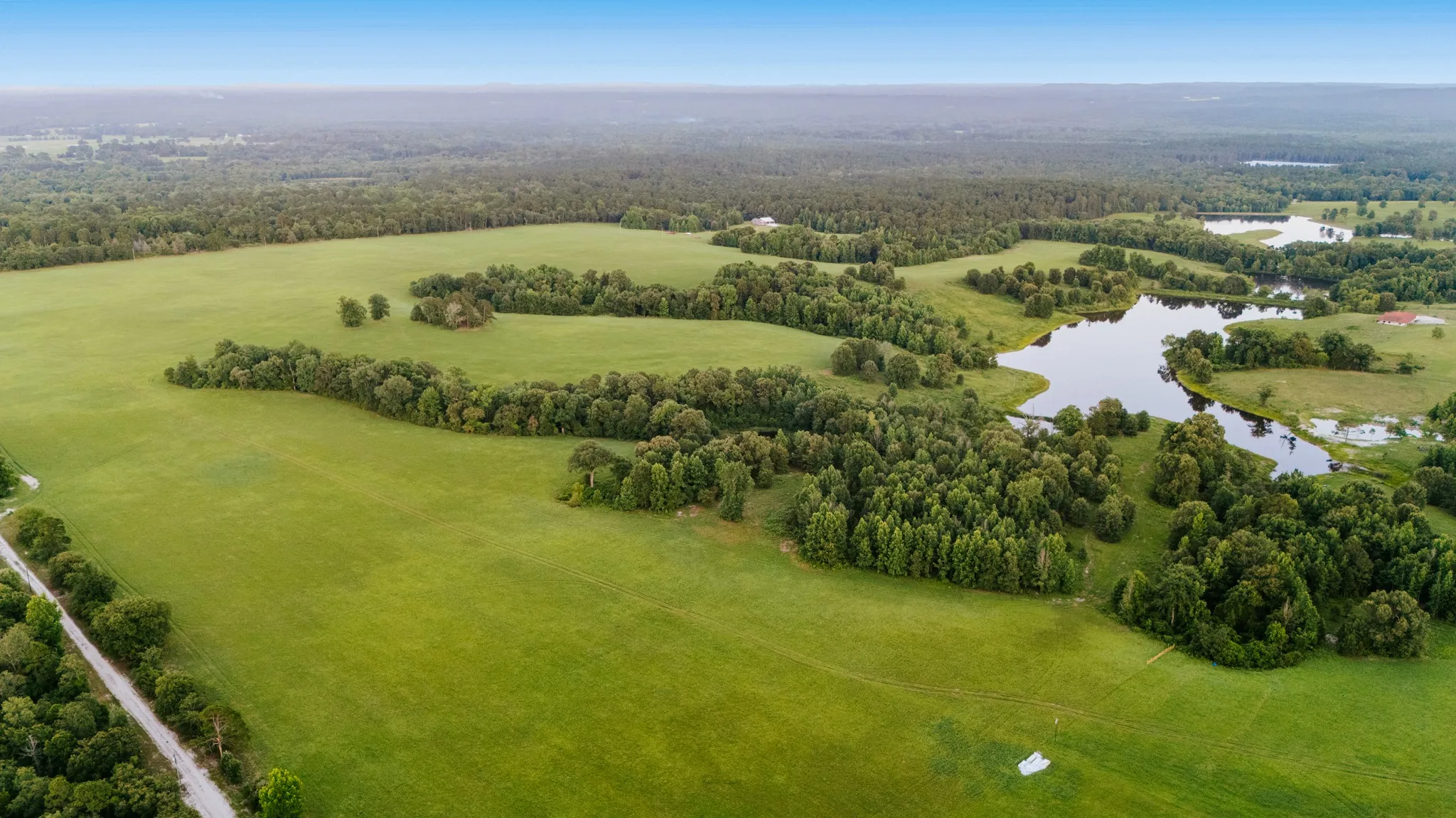 Expansive green pastures and mature tree lines define this rural landscape