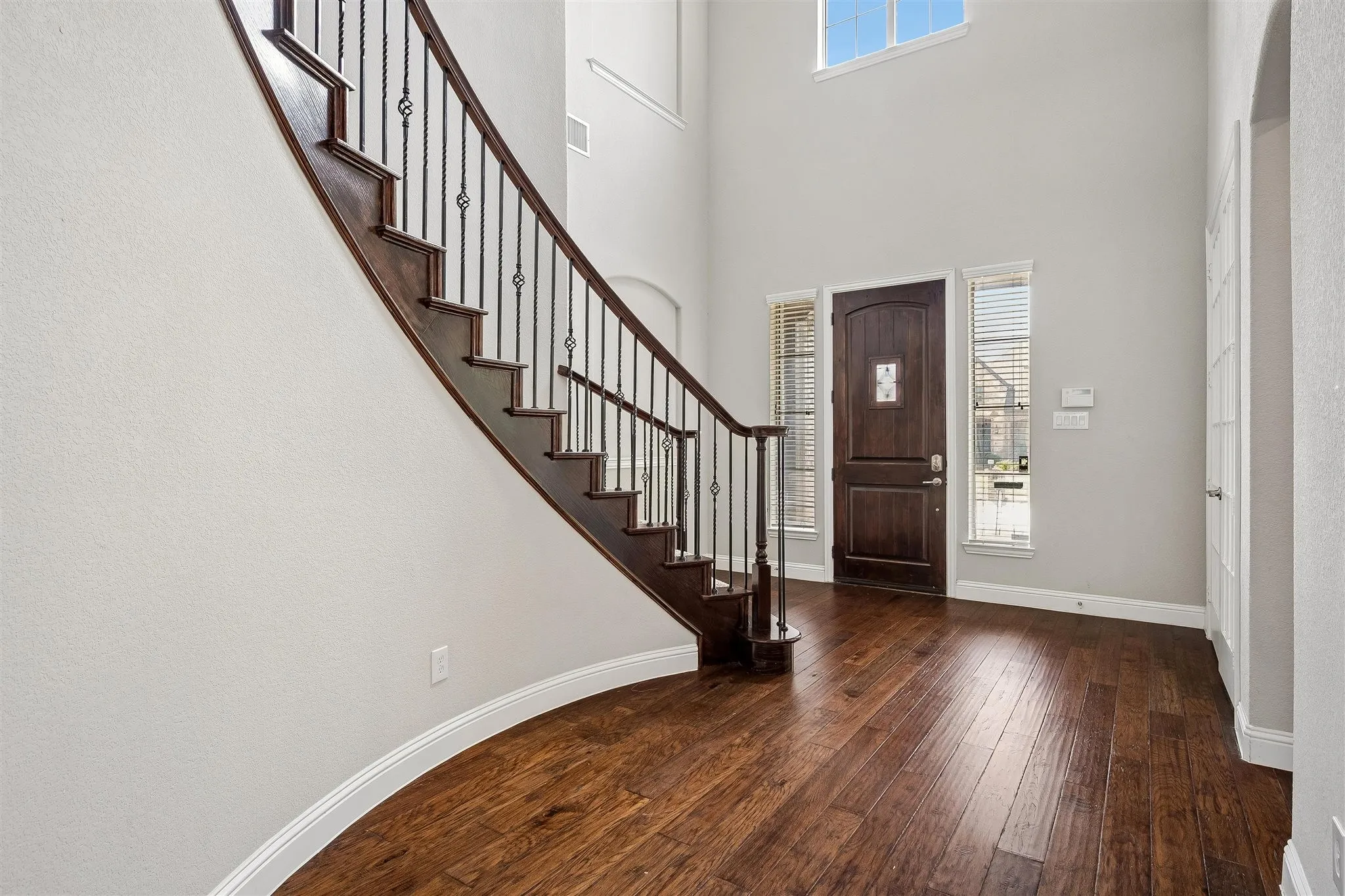 Grand entryway featuring a curved staircase with wrought iron balusters and dark wood treads