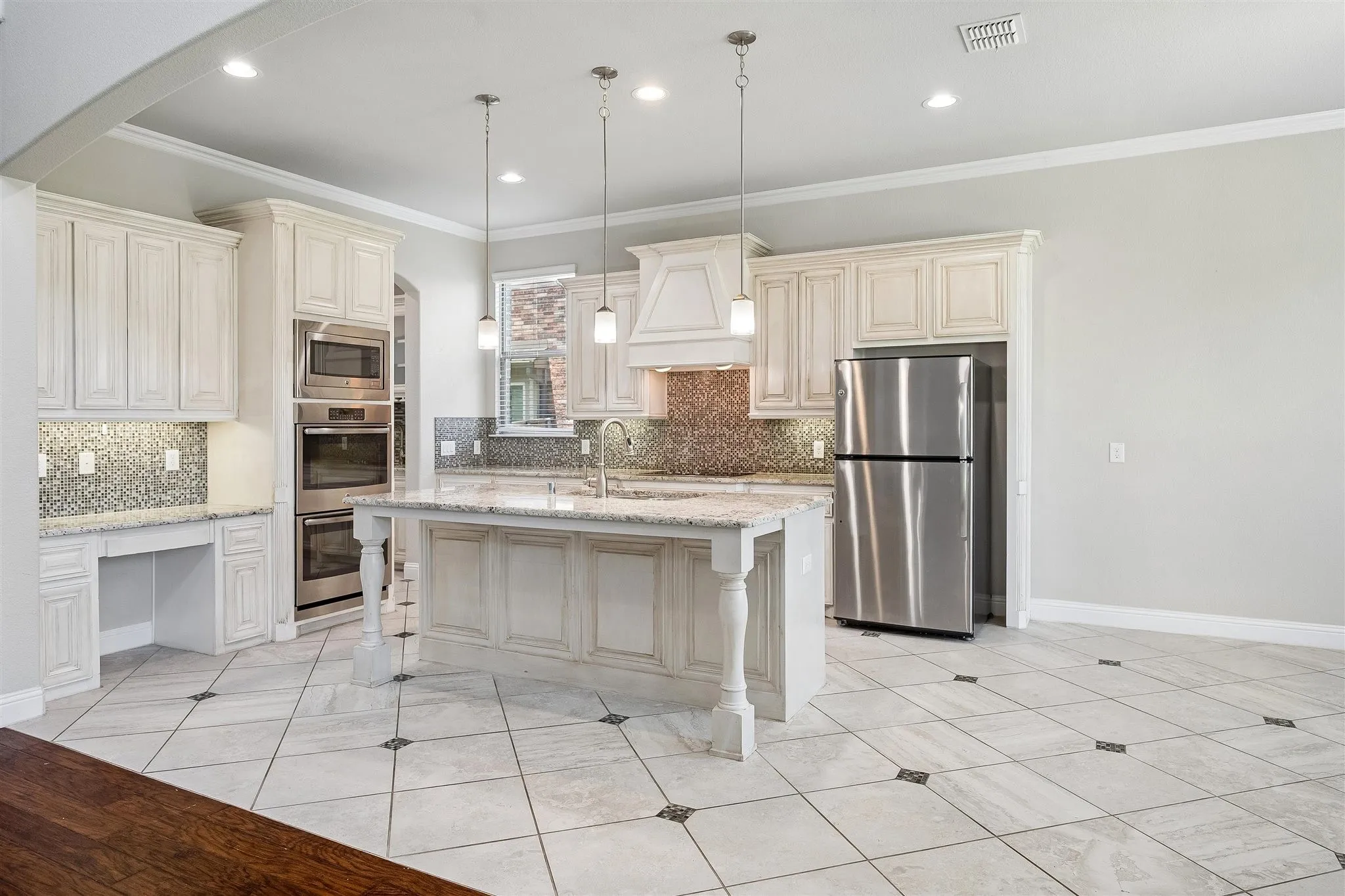 Kitchen featuring white cabinetry, a central island with turned legs, stainless steel appliances, and a mosaic tile backsplash