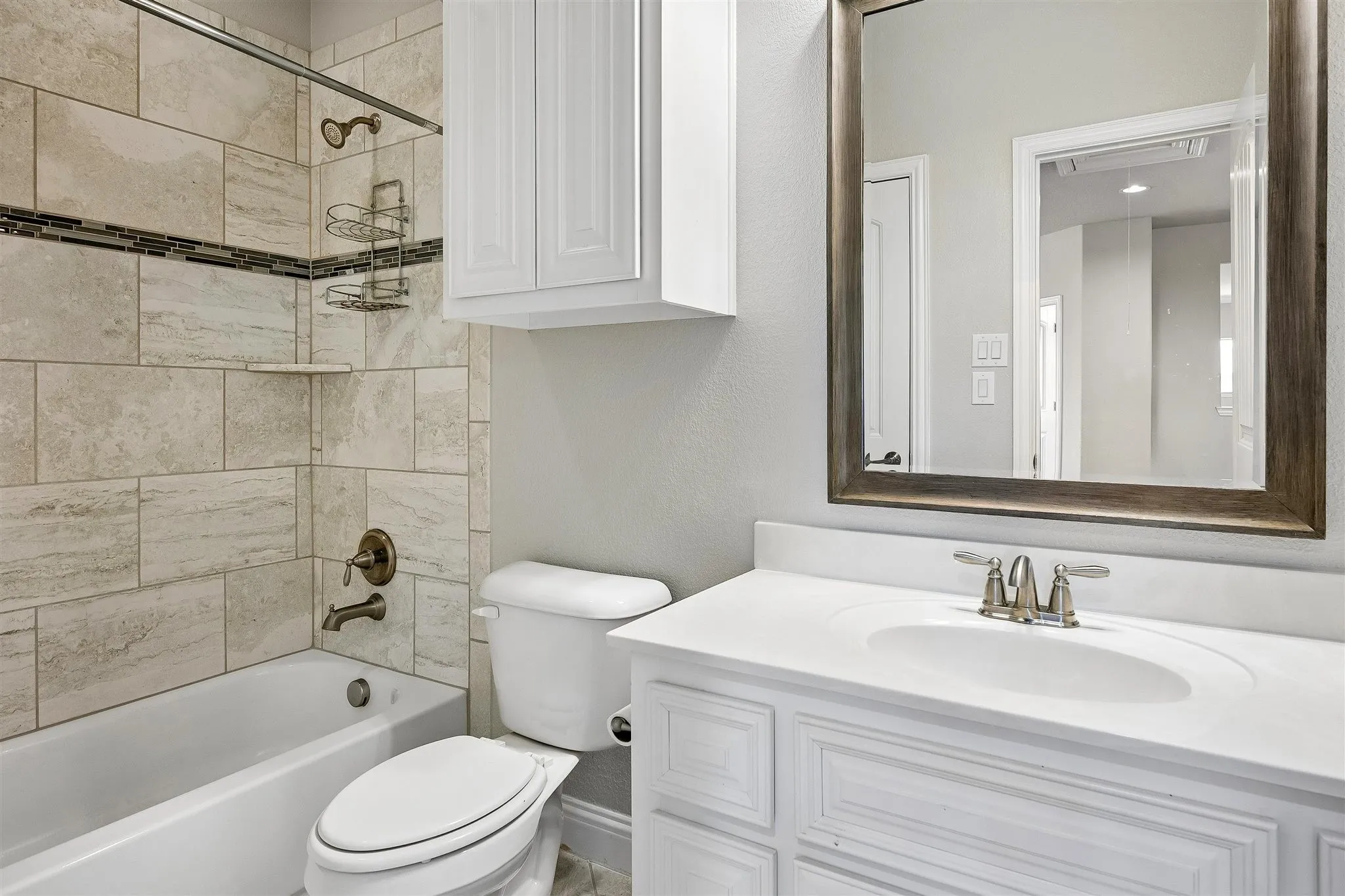 Bathroom featuring a white vanity with an integrated sink, framed mirror, and white cabinetry