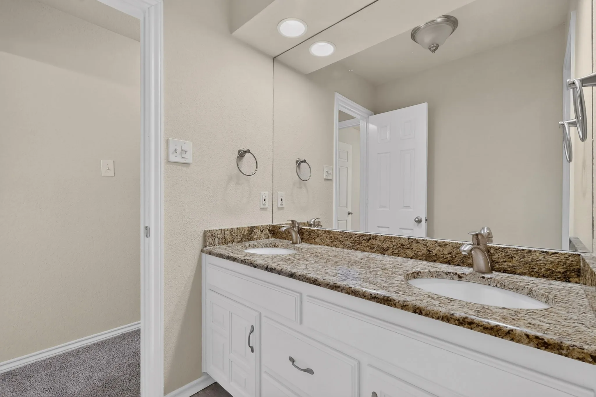 Double vanity featuring granite countertops, undermount sinks, and brushed nickel fixtures