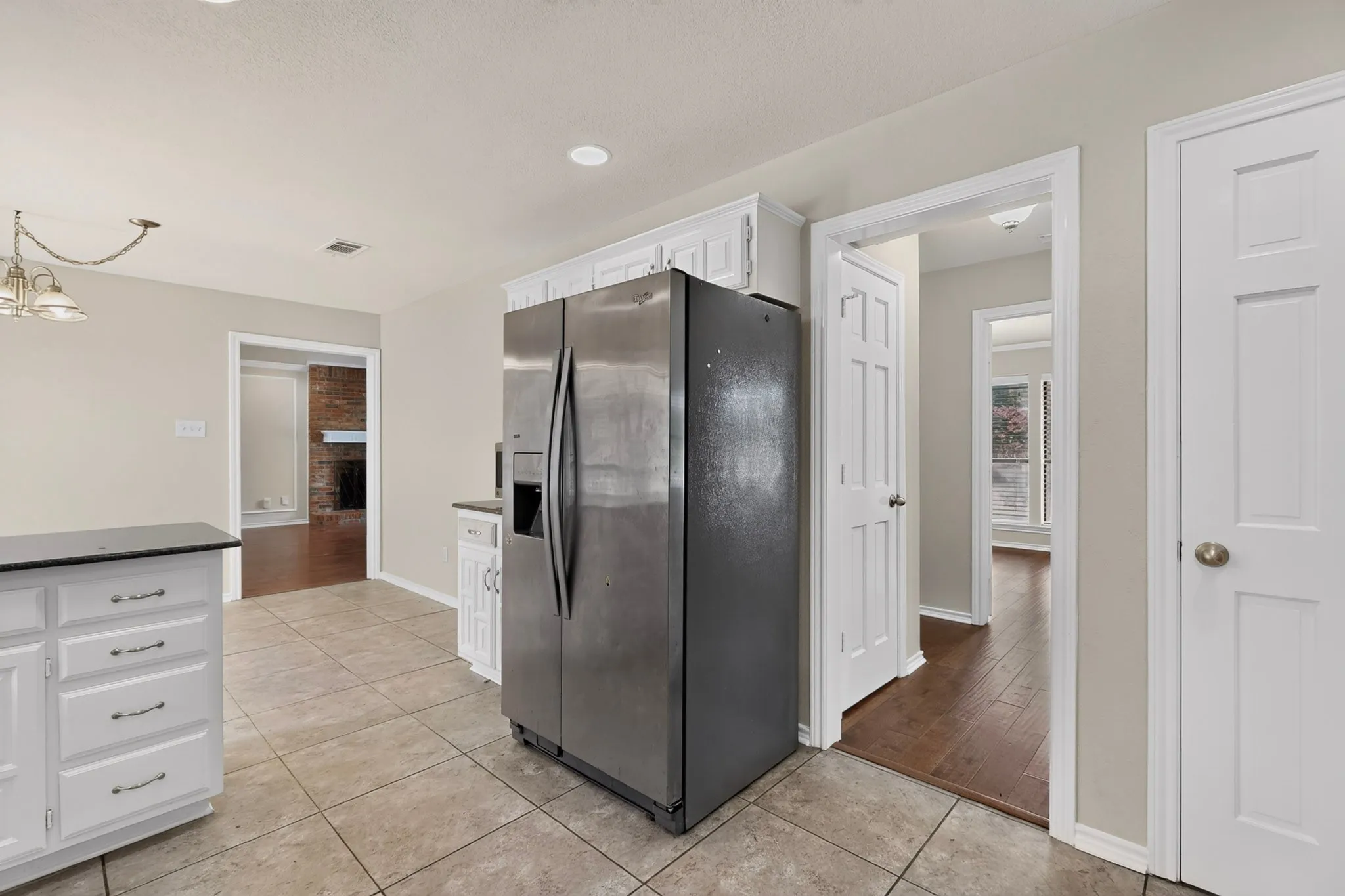 Kitchen area featuring tile flooring, white cabinetry, dark countertops, and recessed lighting