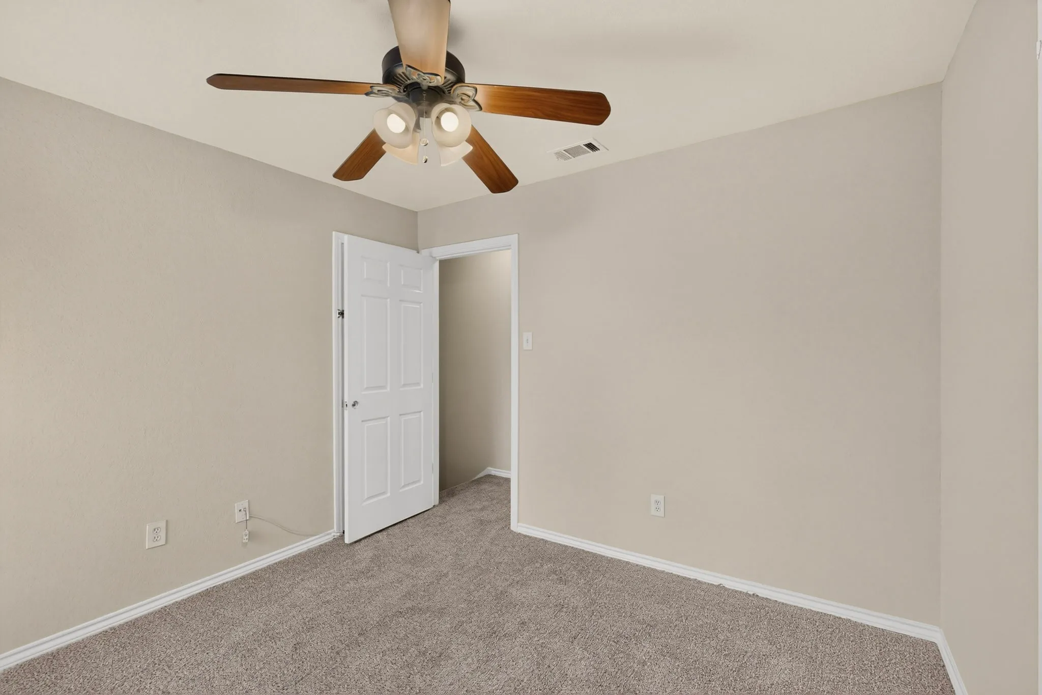 Neutral-toned room featuring a ceiling fan with integrated lighting, textured walls, and carpet flooring