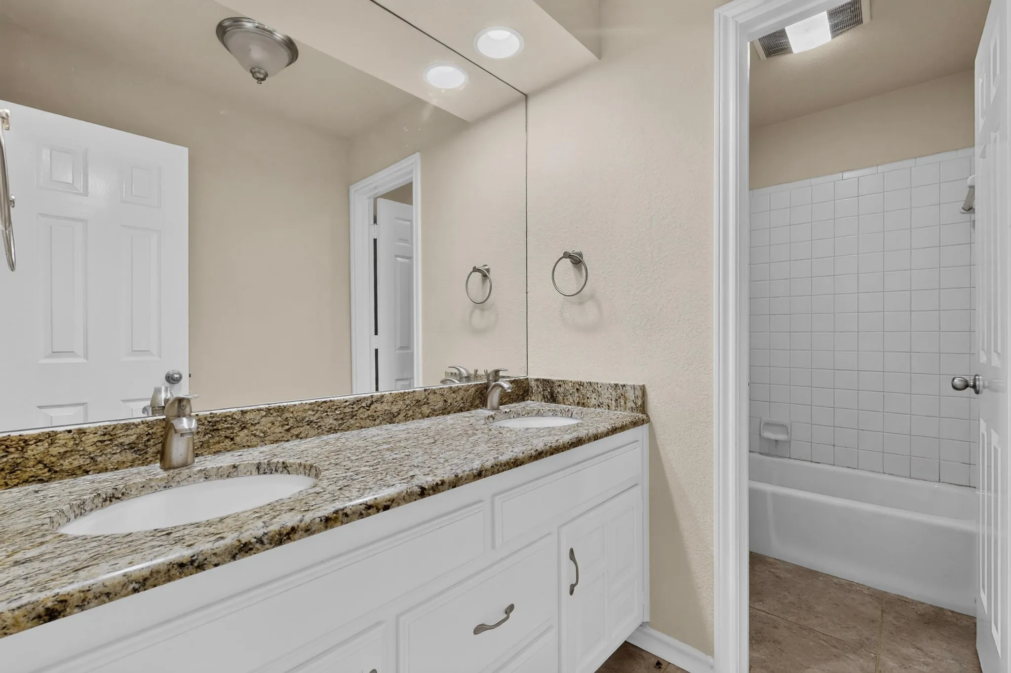 Bathroom featuring a dual vanity with granite-finish countertops and integrated sinks