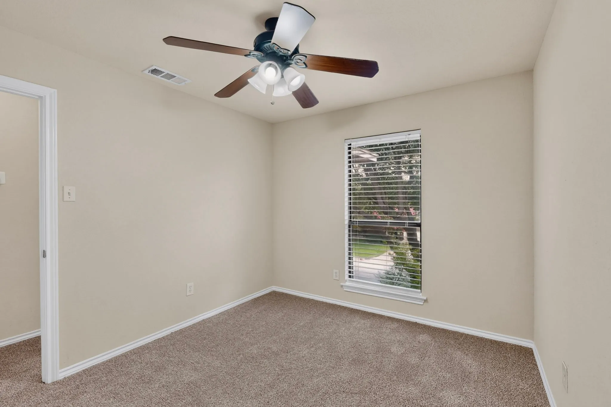 Carpeted room with a ceiling fan light fixture, neutral wall paint, white trim, and a window featuring blinds