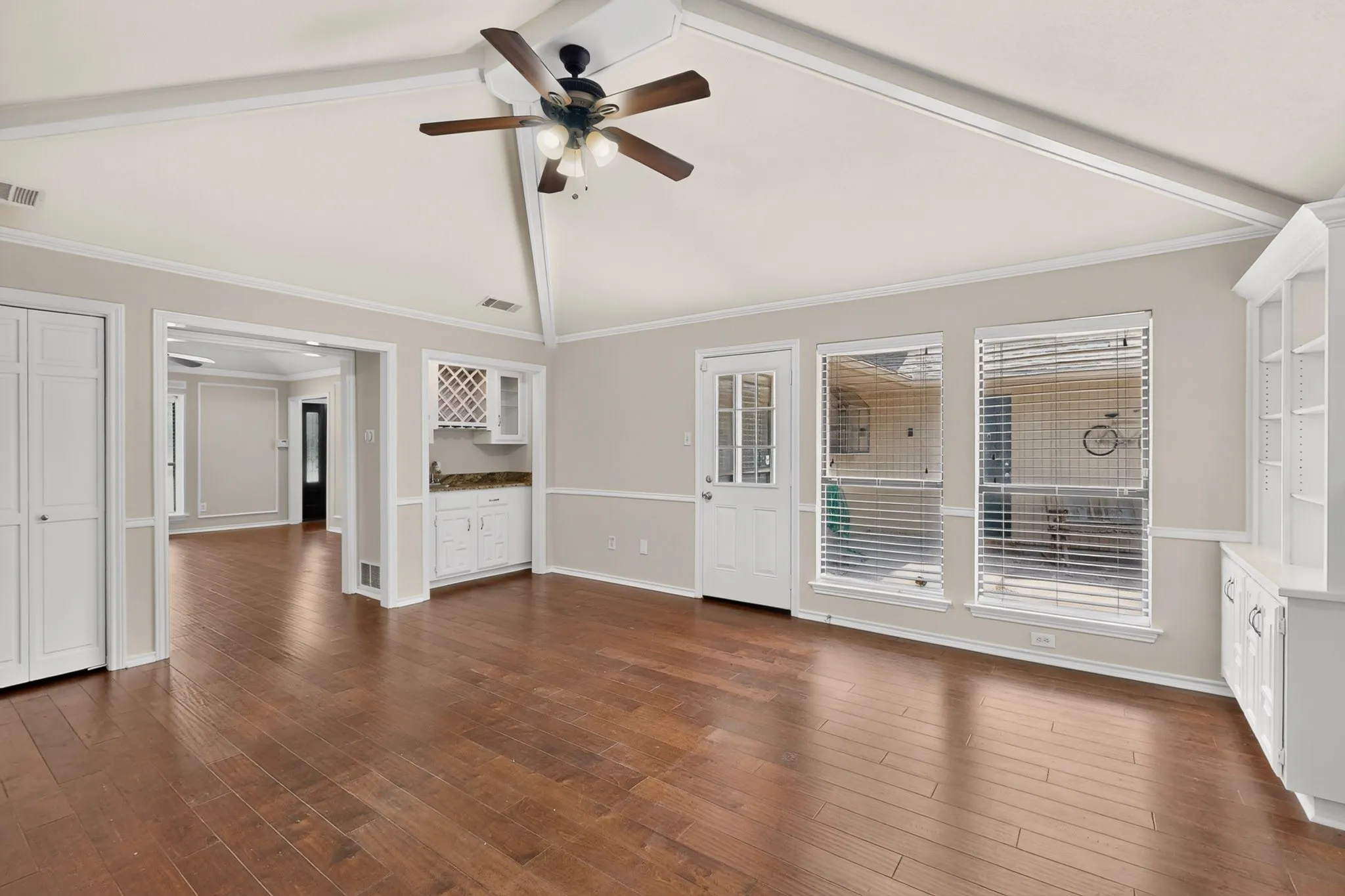 Spacious interior featuring wood-finish flooring, vaulted ceiling with a ceiling fan, and built-in shelving