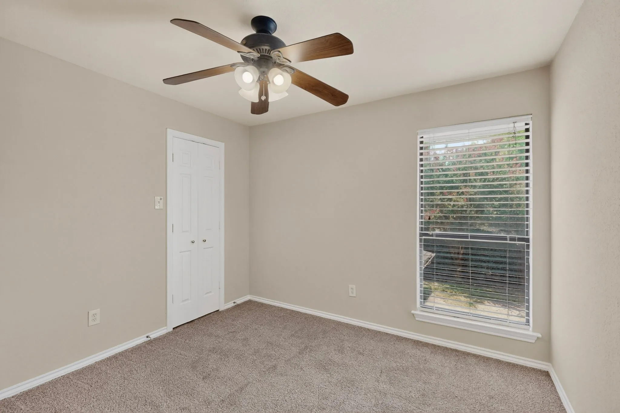 Neutral tone carpeting and walls complement the ceiling fan with integrated lighting