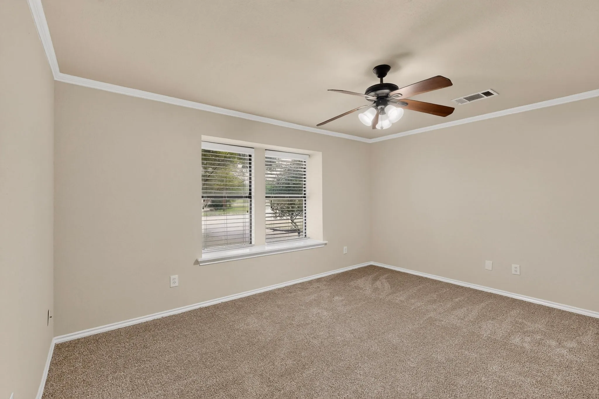 Spacious room featuring neutral carpet flooring, light-toned wall paint, and white crown molding