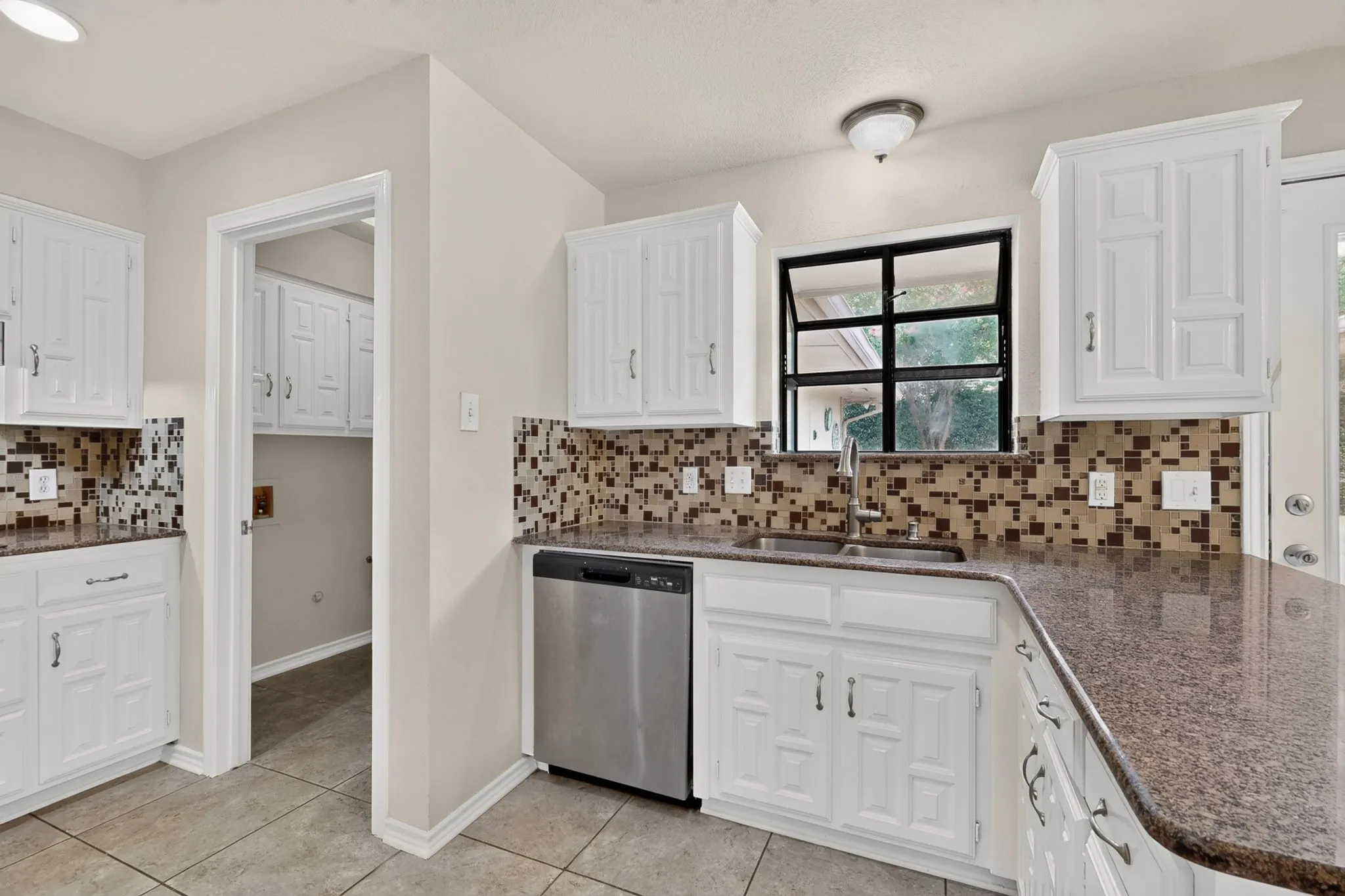 Kitchen featuring white cabinetry, granite countertops, and a mosaic tile backsplash