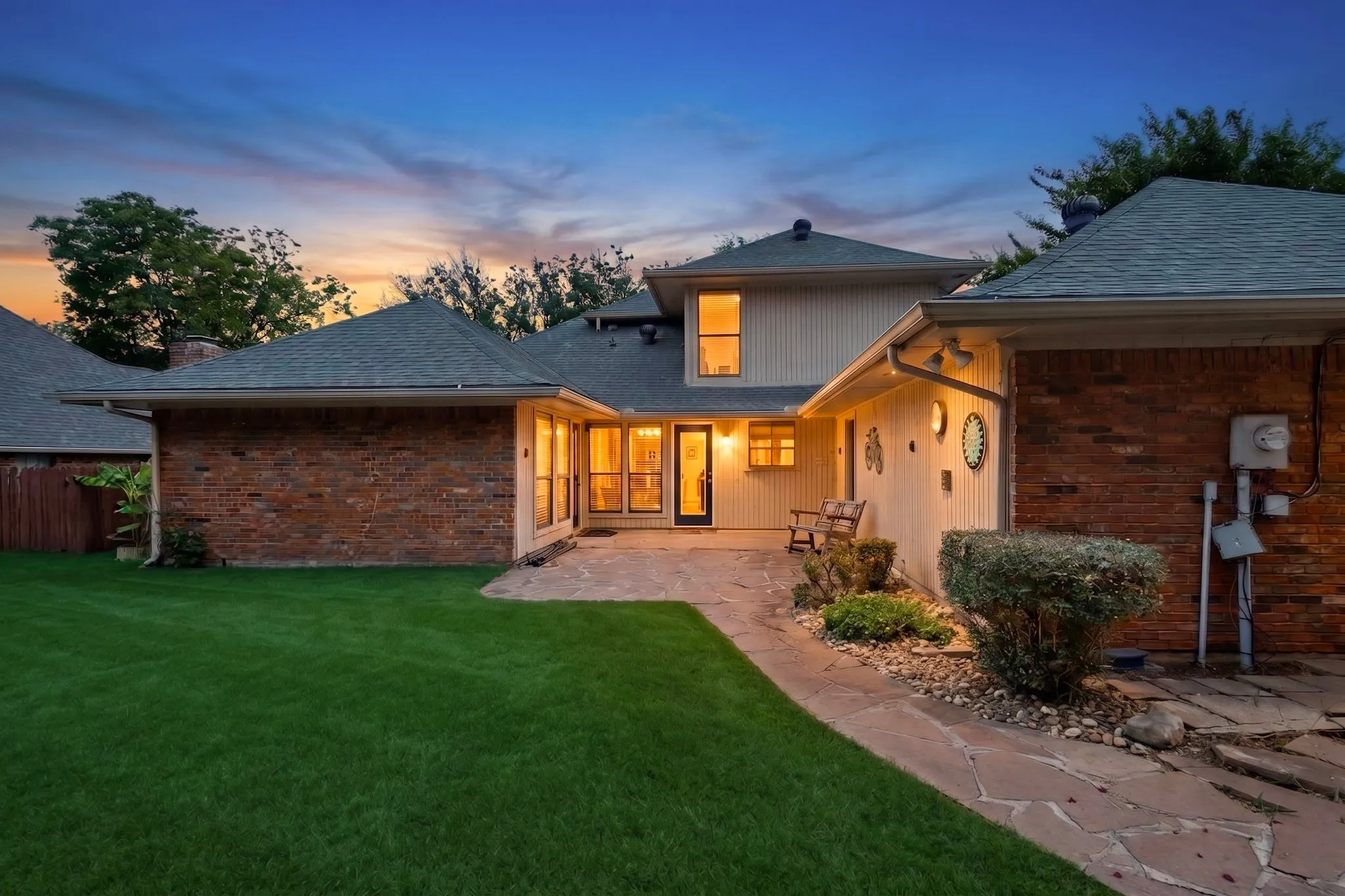 Expansive green lawn bordering a flagstone patio with a direct entry point to the property