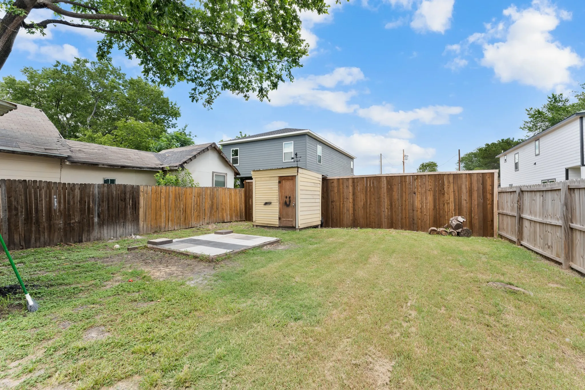 Expansive backyard featuring a lush lawn, privacy fencing, and a detached storage shed