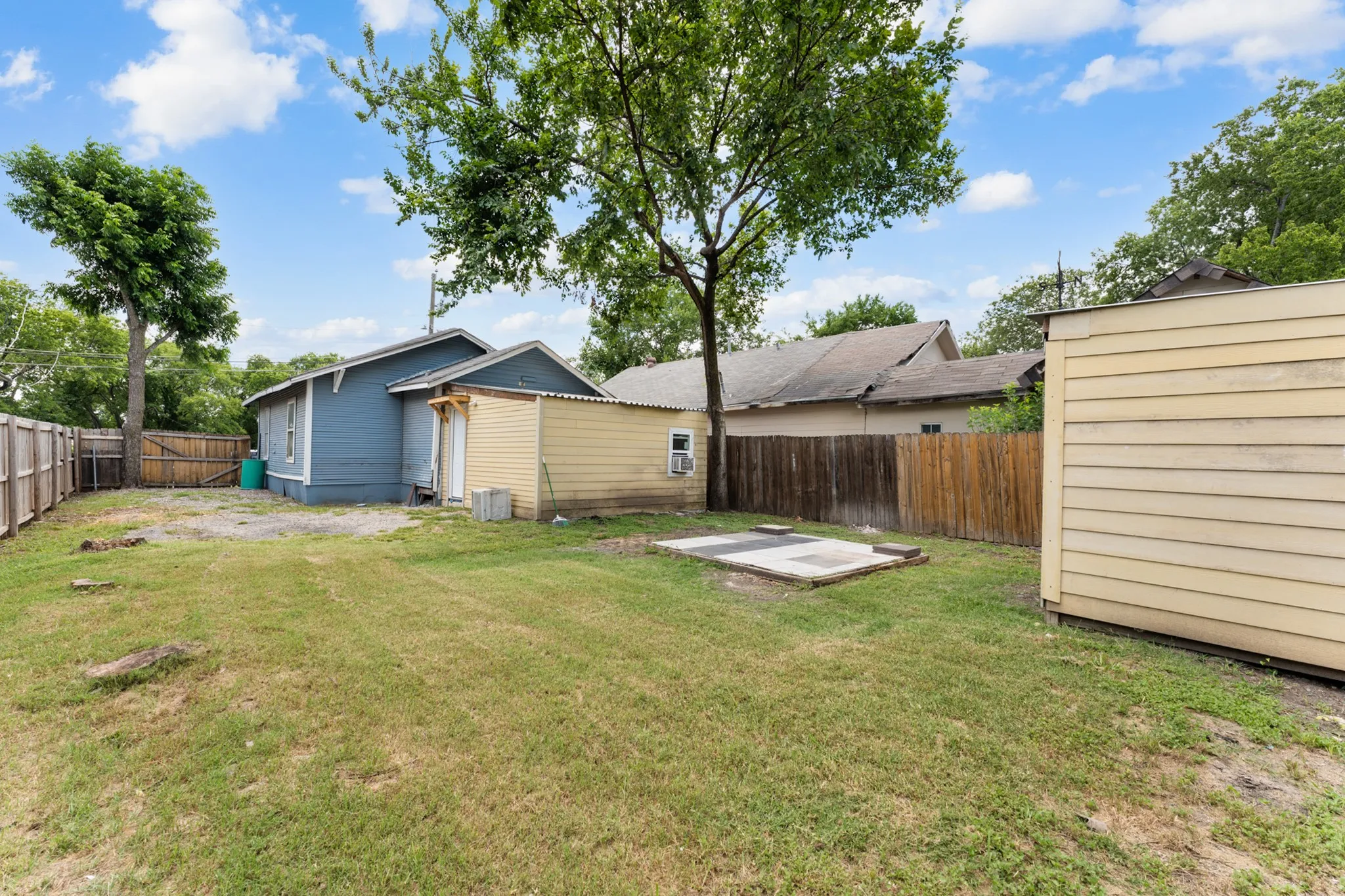 Expansive backyard featuring a wood fence, a detached shed, a concrete pad, and mature trees