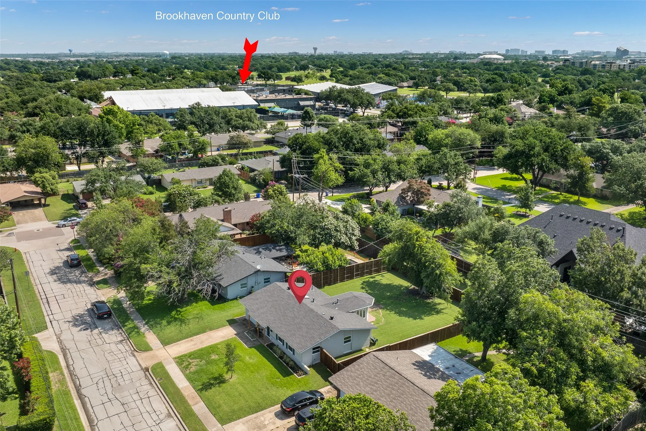Aerial perspective showcasing a single-story residence with a dark shingle roof and a spacious, fenced backyard