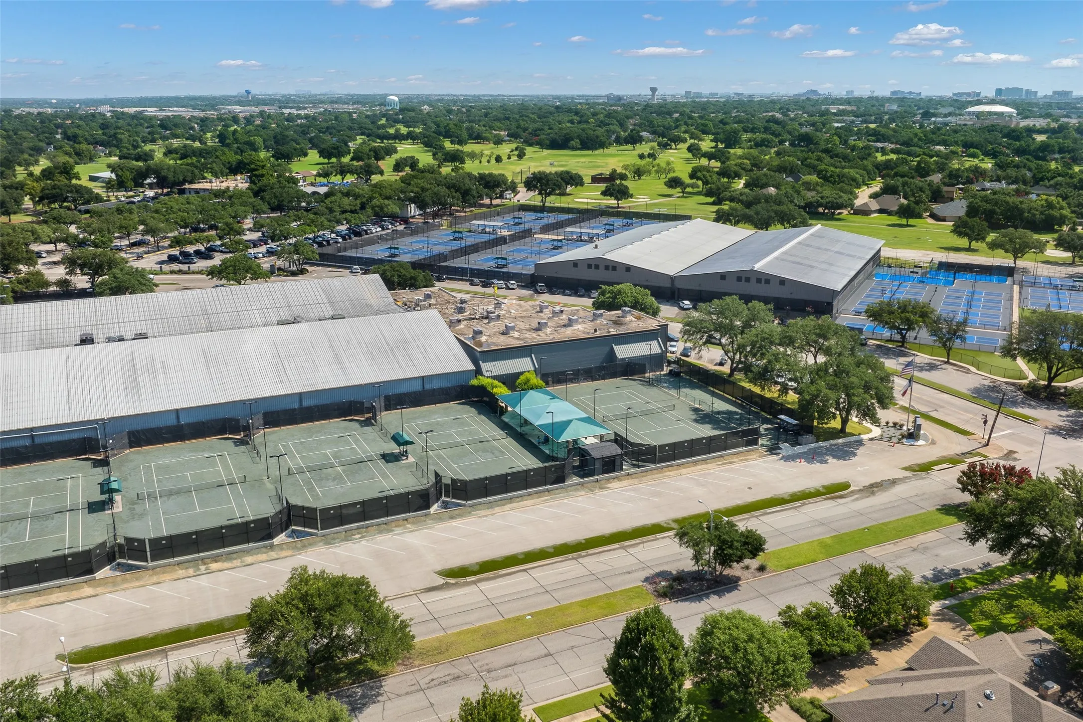 Expansive tennis facility featuring multiple outdoor courts, covered courts, and a separate clubhouse building