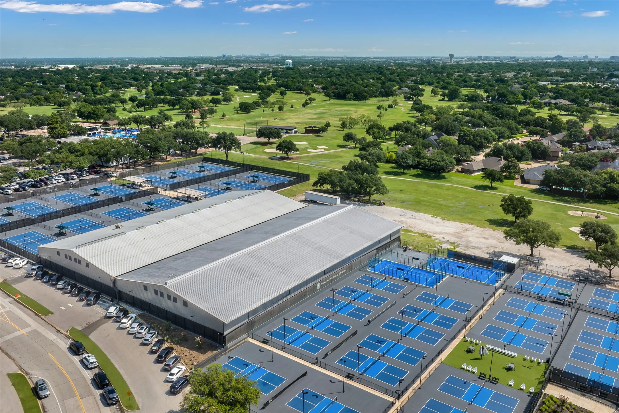Extensive athletic facility featuring multiple outdoor courts, an indoor court structure, and ample parking