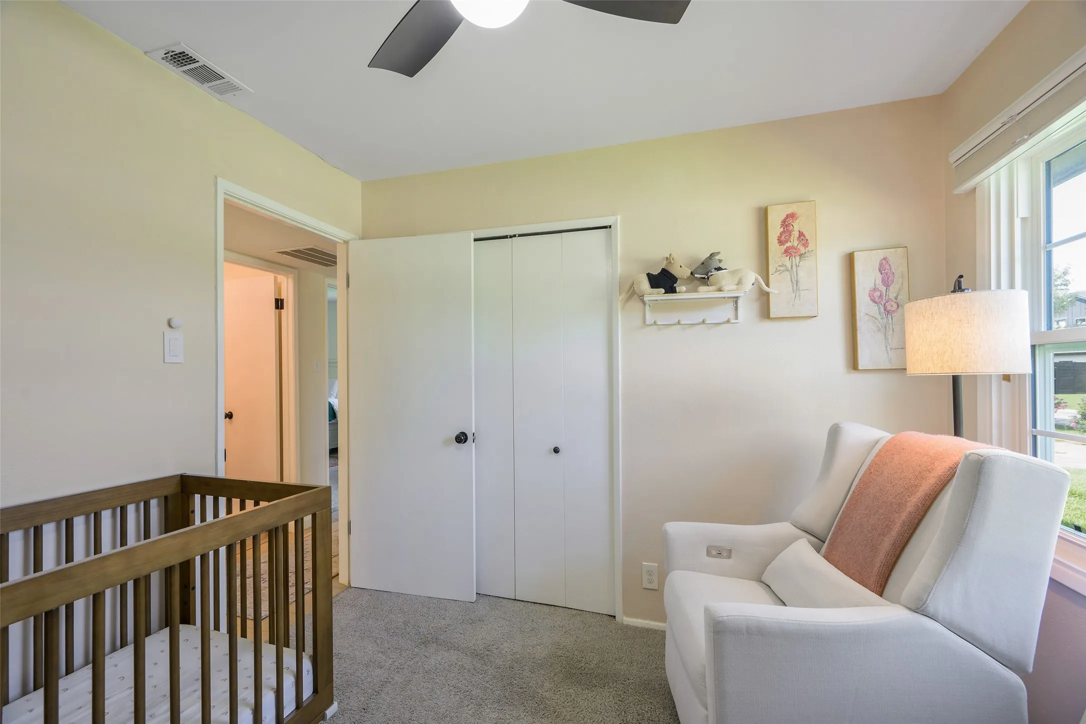 Carpeted room featuring a ceiling fan, window with blinds, and white bi-fold closet doors