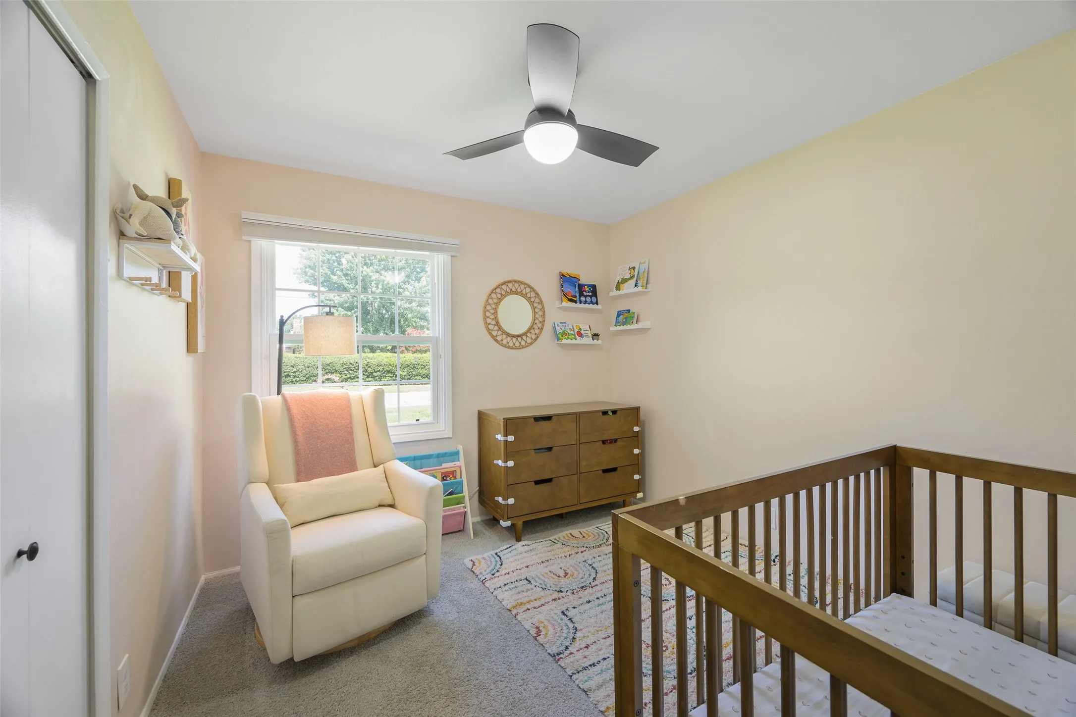 Bright room featuring neutral-toned walls, a window with exterior tree-line visibility, and a ceiling fan with integrated lighting