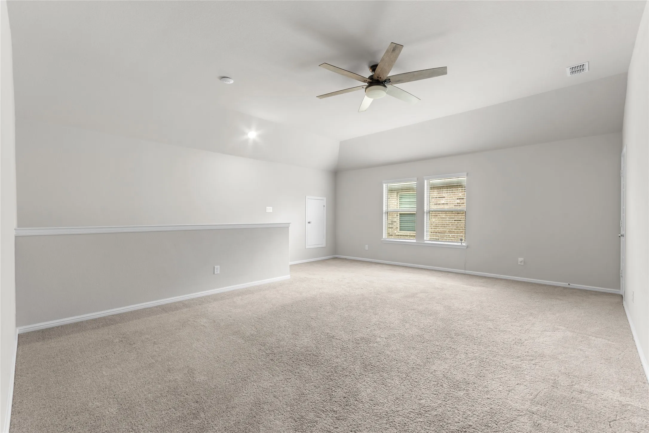 Spacious carpeted room featuring vaulted ceilings, a ceiling fan with light fixture, recessed lighting, and twin windows