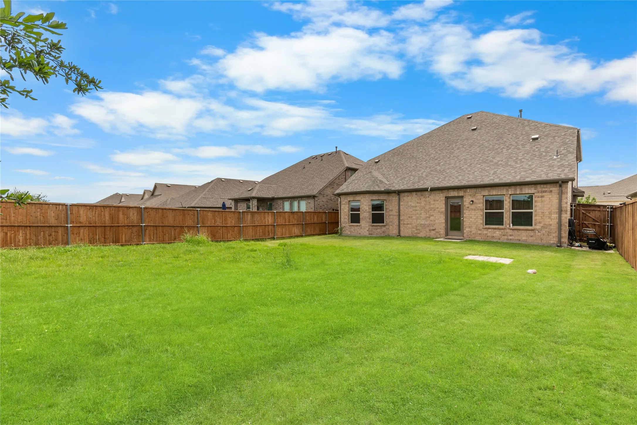 Expansive green lawn with a full privacy fence