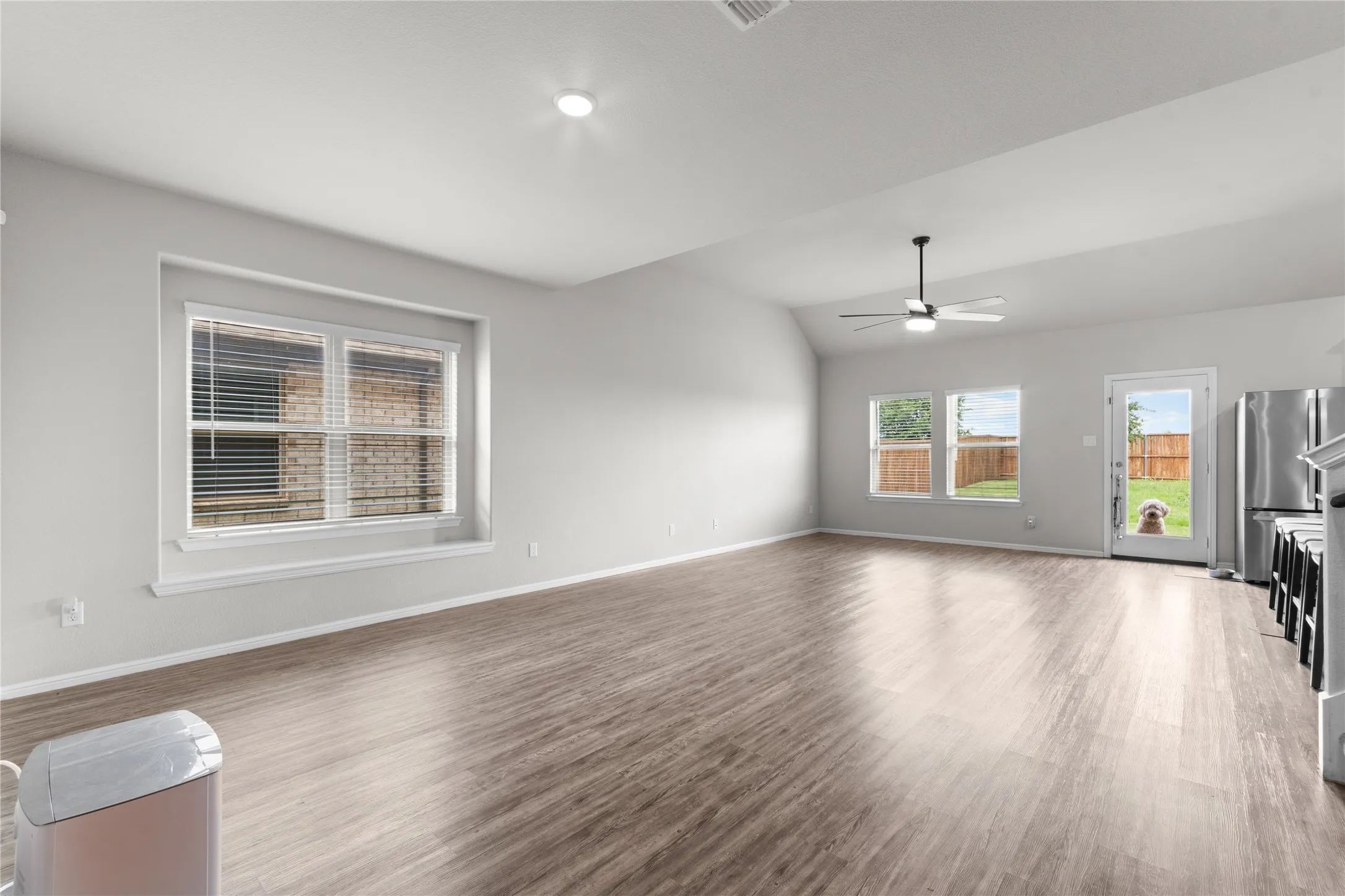 Spacious open-concept room featuring wood-finish flooring, vaulted ceilings, and recessed lighting
