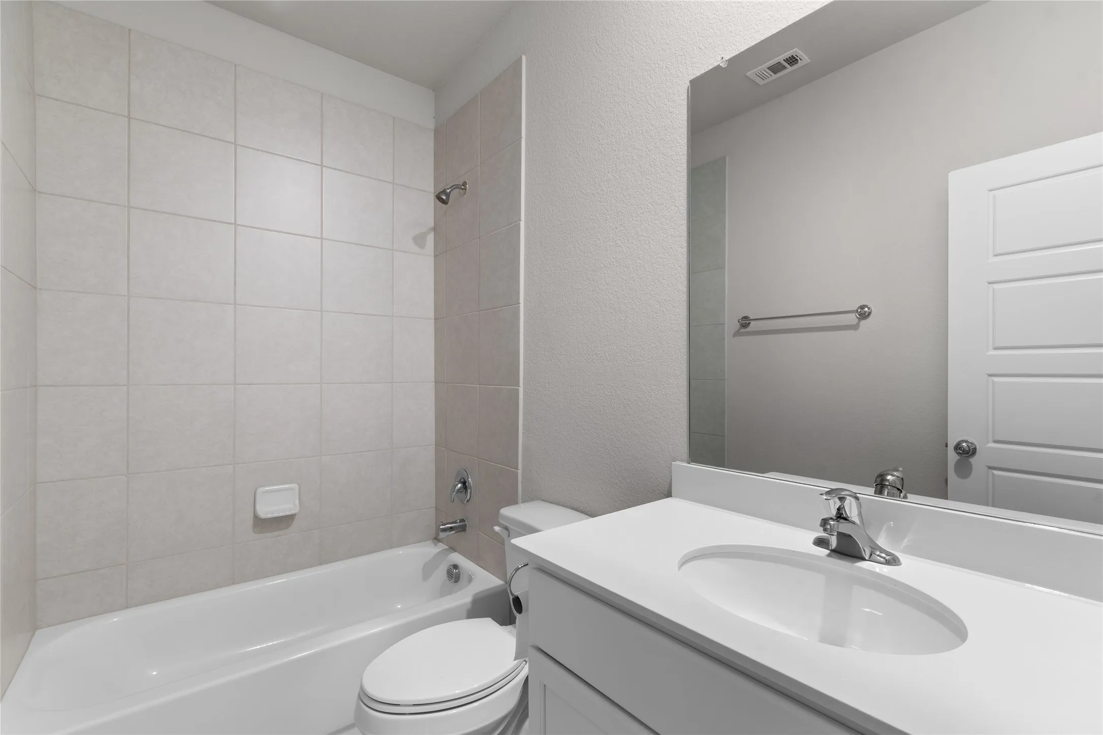 Bathroom featuring a single vanity with an integrated sink, polished chrome faucet, full-width mirror, and a tiled tub-shower combination