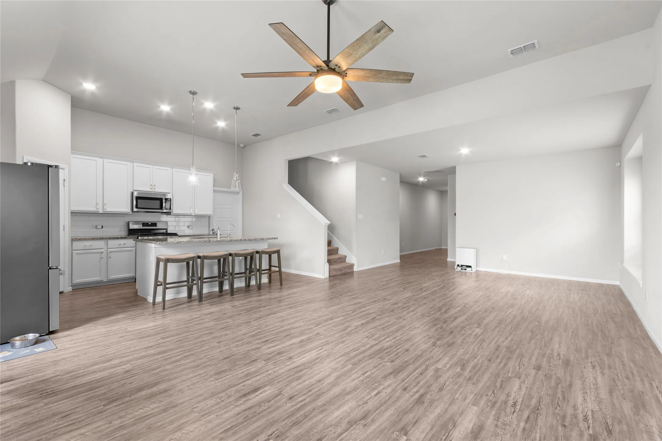 Open-concept living area featuring wood-finish flooring, recessed lighting, and a contemporary ceiling fan