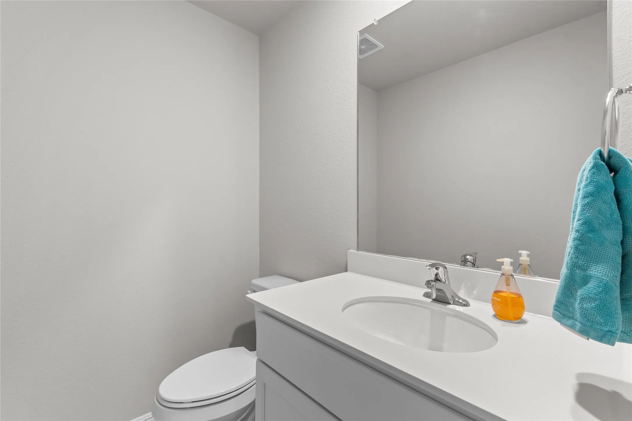 Bathroom vanity featuring a built-in sink, chrome faucet, white countertop, and integrated mirror