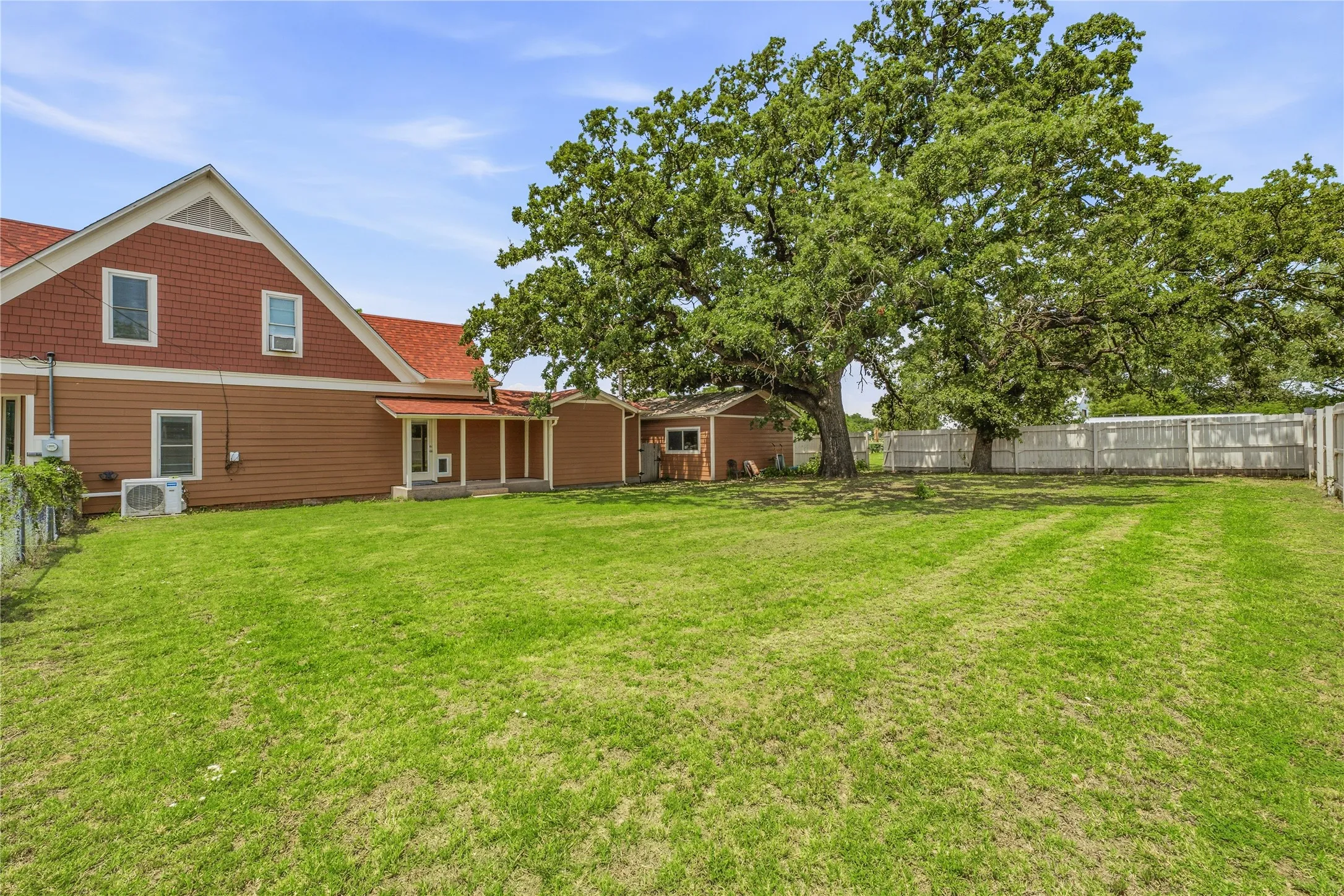 Expansive grassy yard featuring mature shade trees