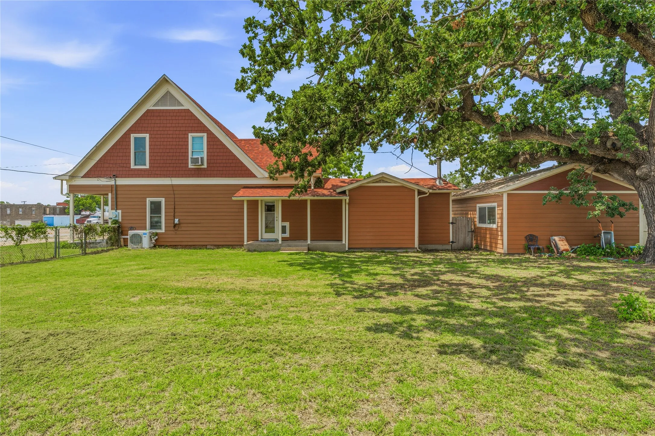 Expansive green lawn with mature tree providing shade