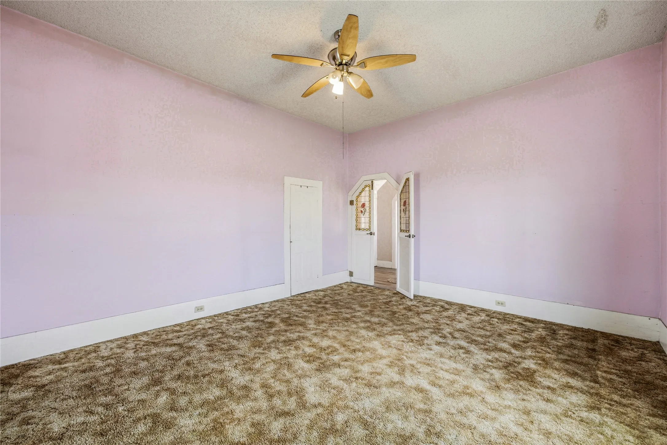 Room featuring a ceiling fan with light fixture, textured ceiling, and purple walls with white trim