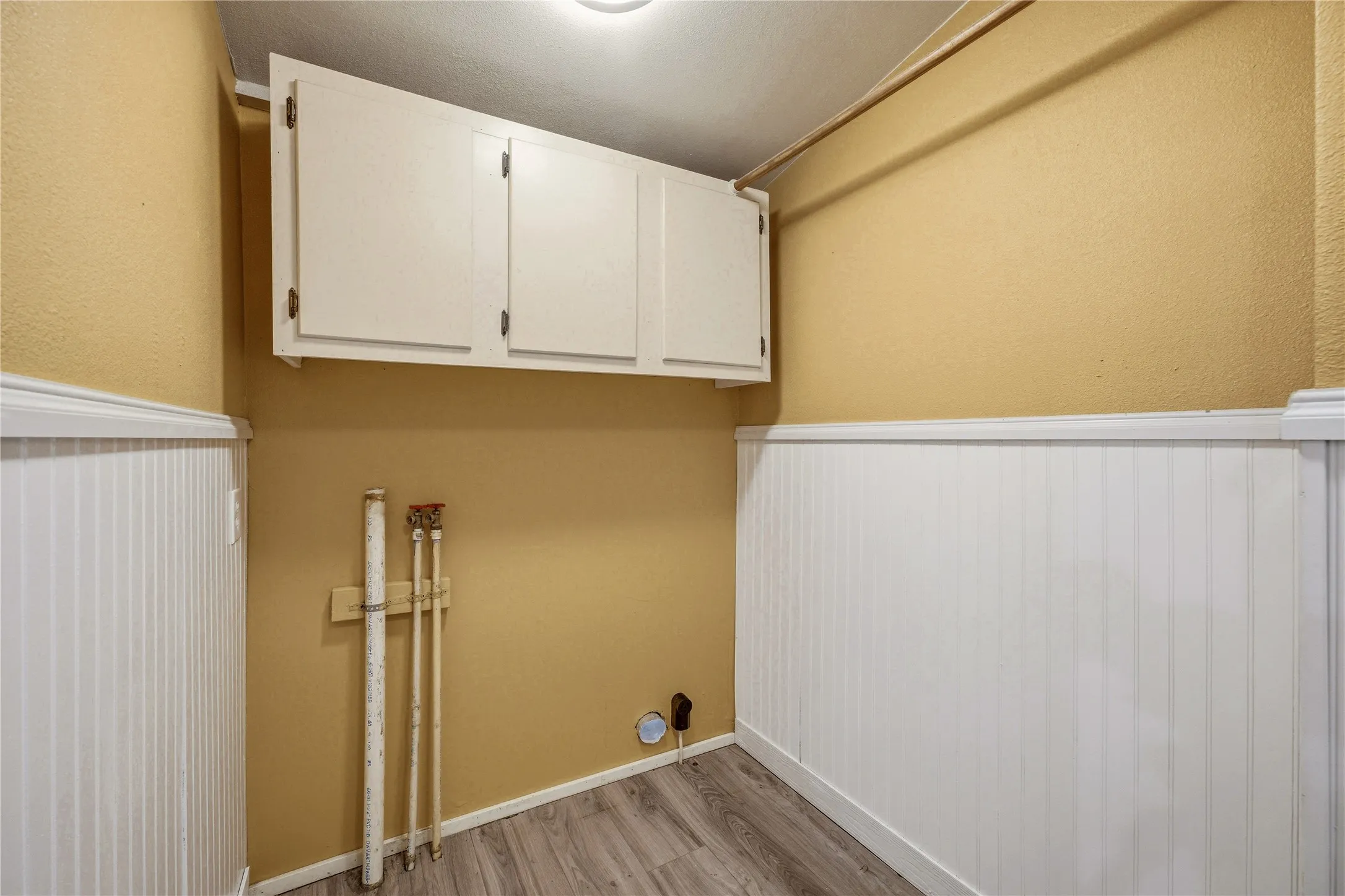 Laundry area featuring wood-finish flooring and white beadboard paneling