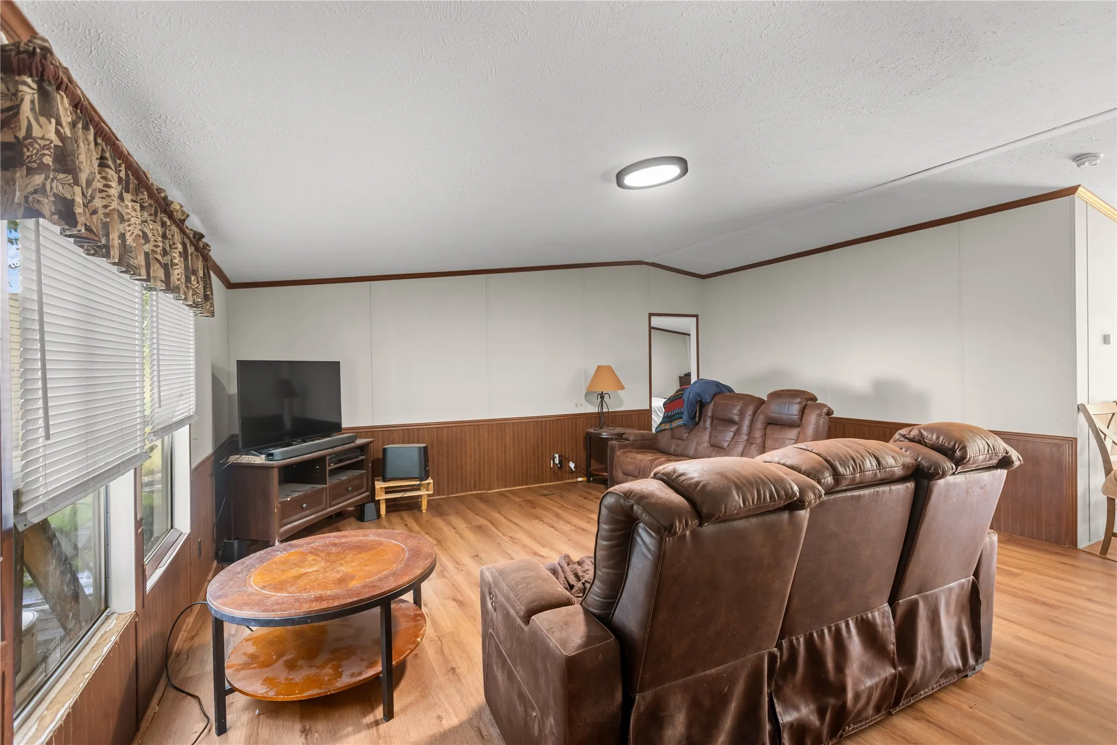Living area featuring wood-finish flooring, white walls, and wood paneling on the lower​​‌​​​​‌​​‌‌​‌‌​​​‌‌​‌​‌​‌​​​‌​​ walls