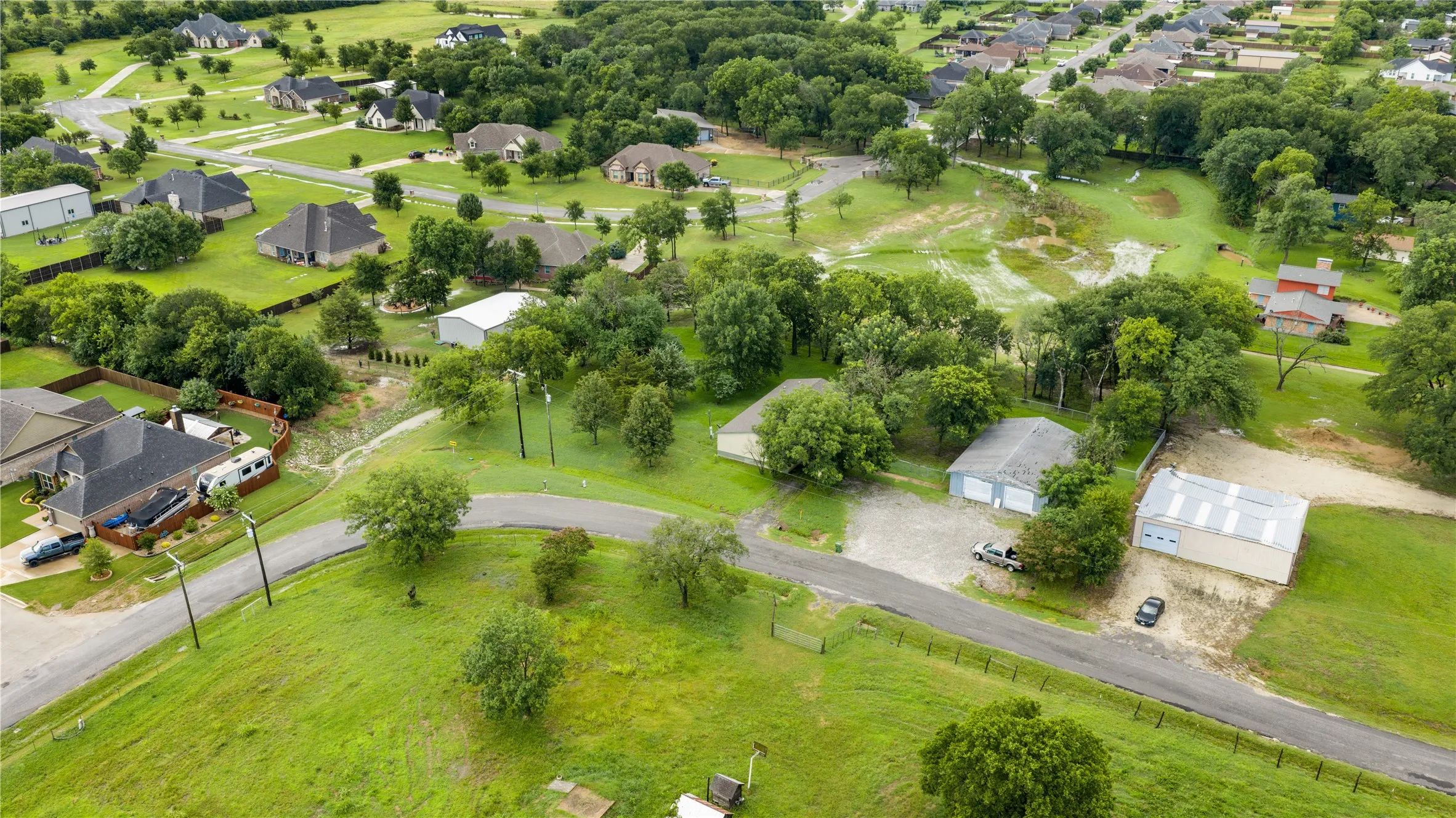 Expansive property parcel featuring a two-car garage, a separate large metal utility building, and a private paved drive
