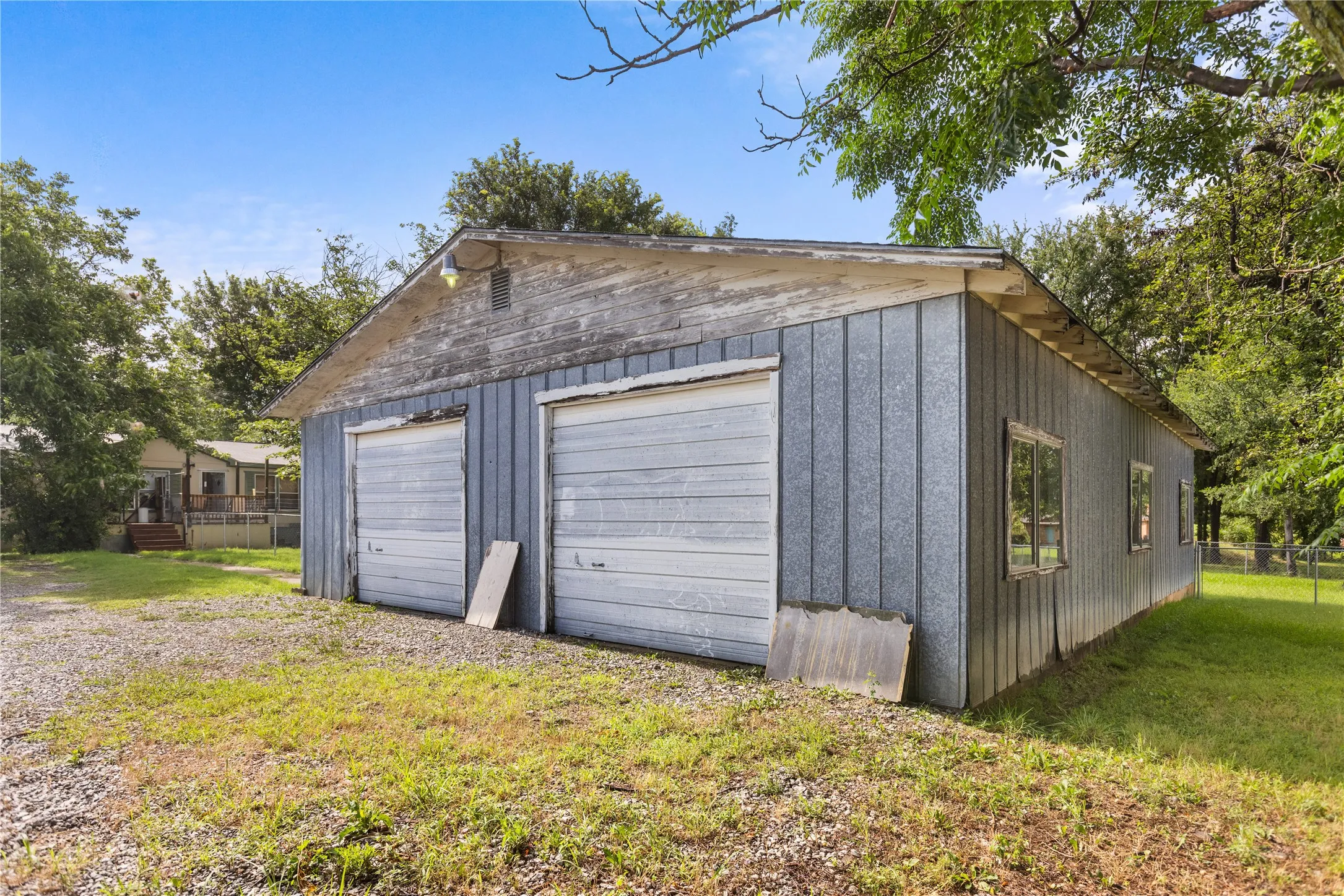 Two-bay garage building with corrugated metal siding, dual roll-up doors, and multiple windows
