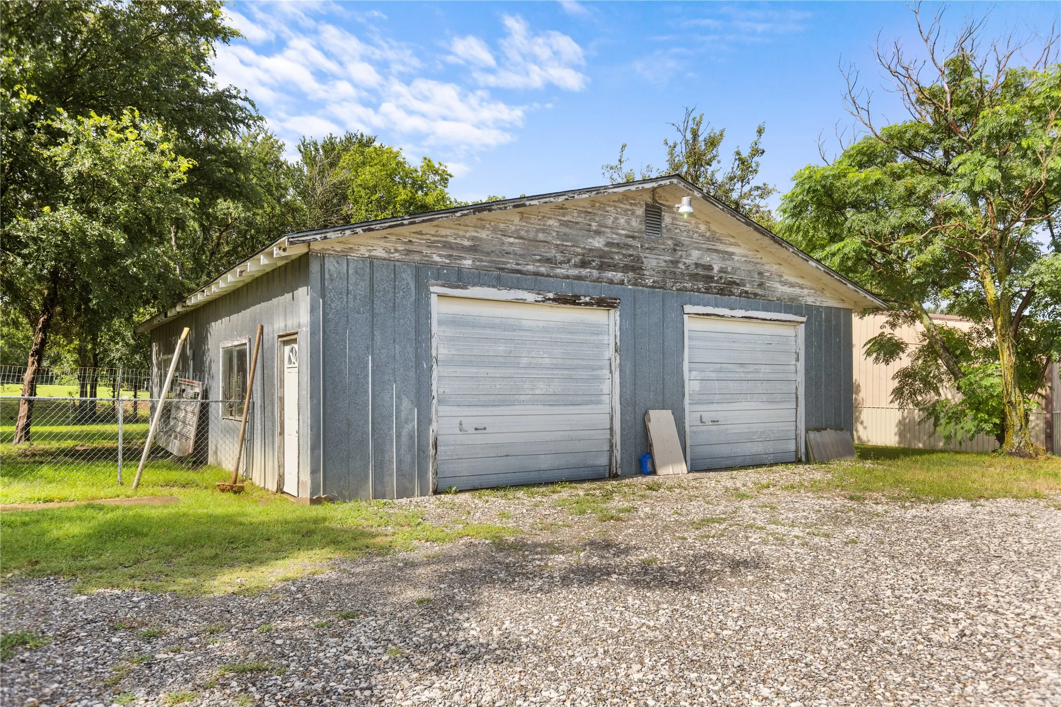 Detached two-car garage with corrugated metal siding, two roll-up doors, and a side entry door