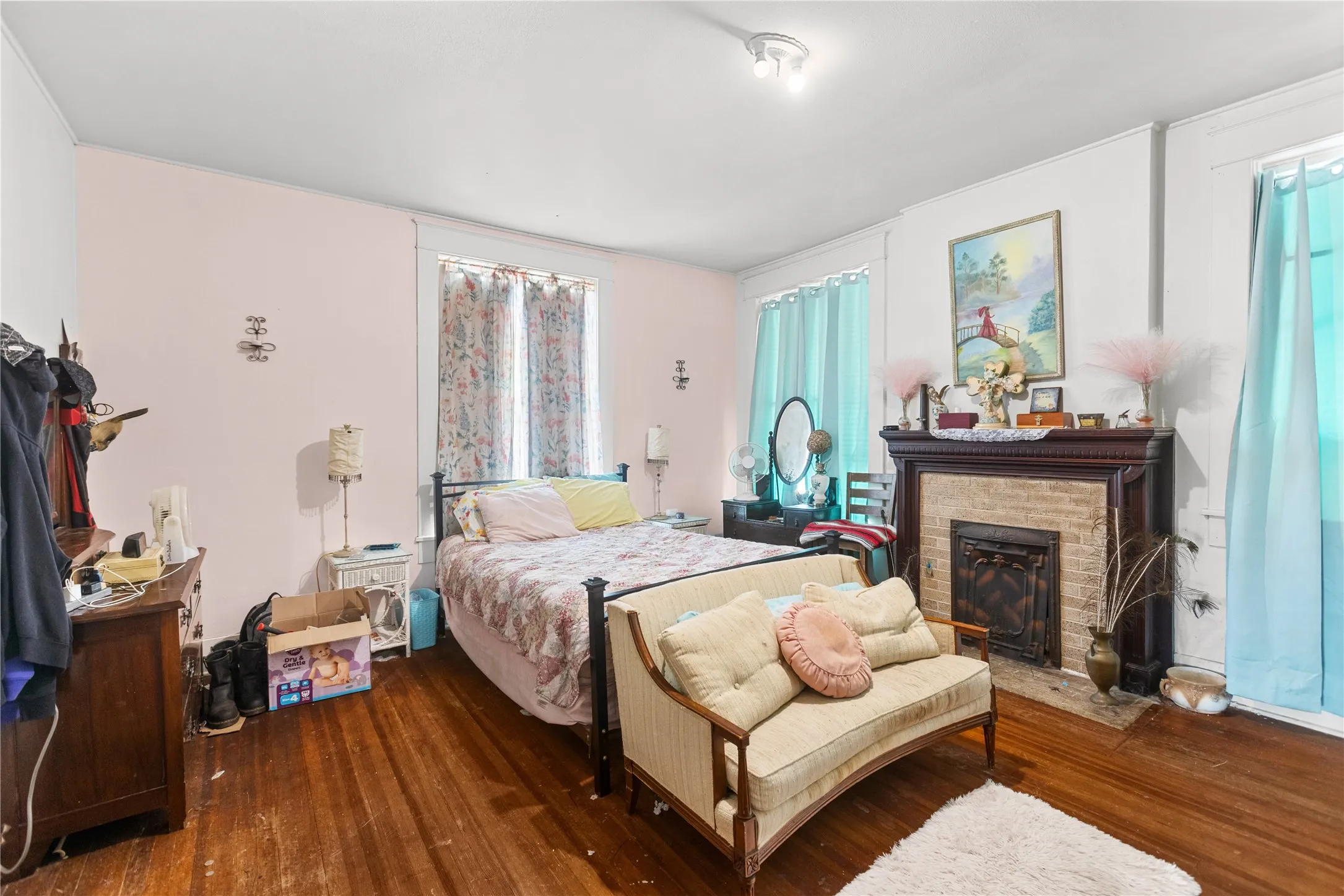 Hardwood flooring complements a decorative fireplace featuring a brick surround and an ornate dark wood mantel