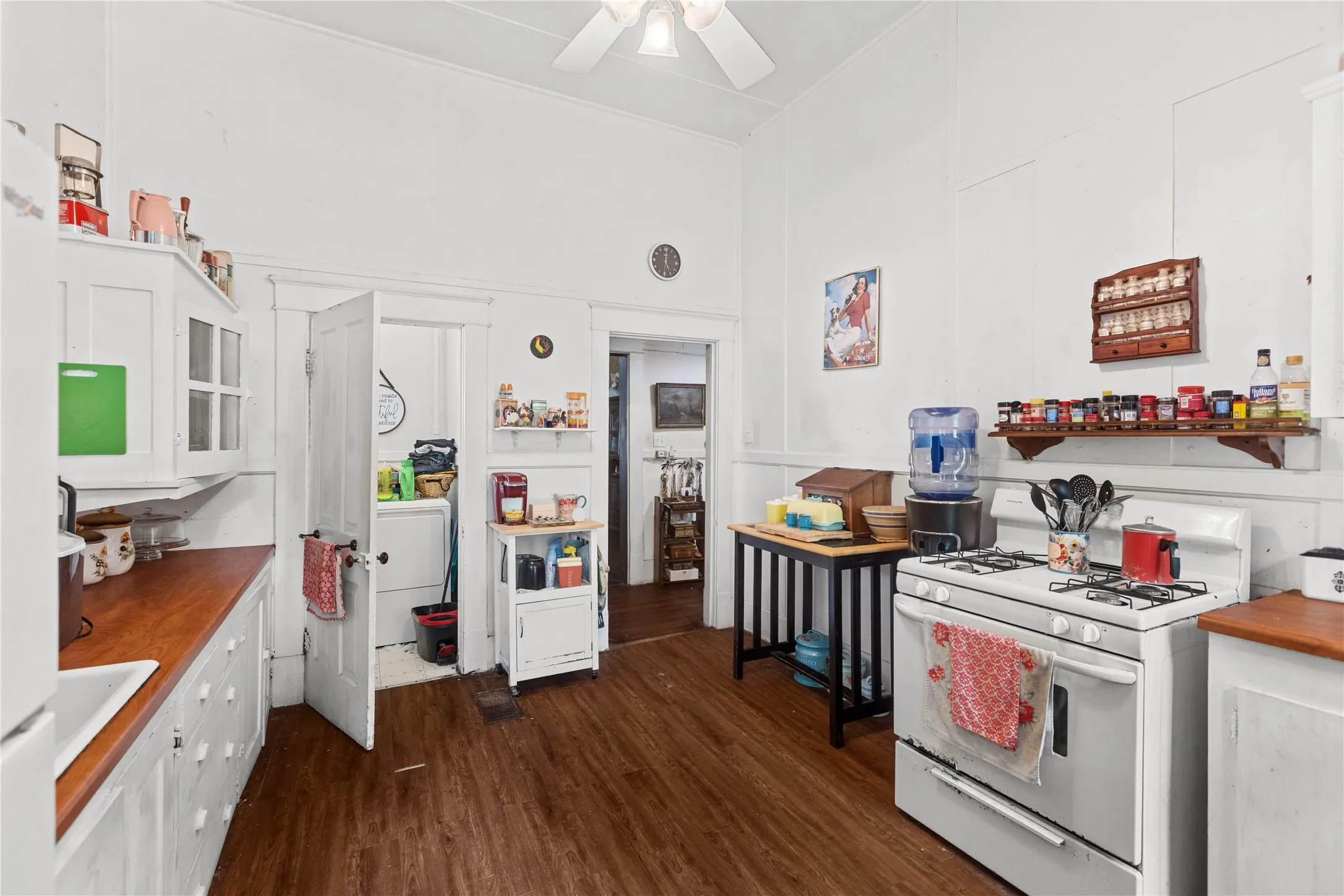 Kitchen featuring wood-finish flooring, white cabinetry, and wood-finish countertops