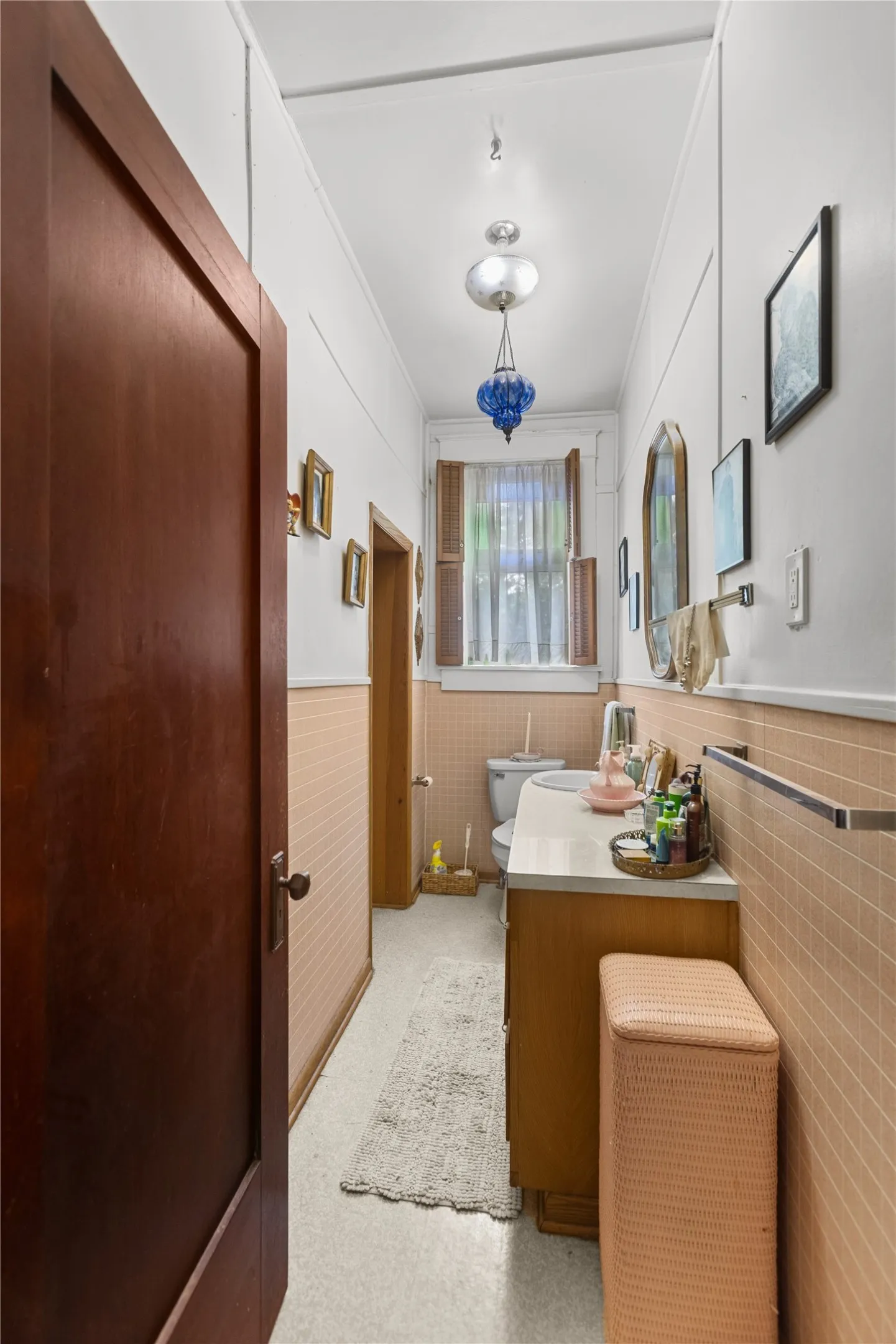 Bathroom featuring light wood-finish vanity with a white countertop, patterned wall tiling, and light-colored flooring