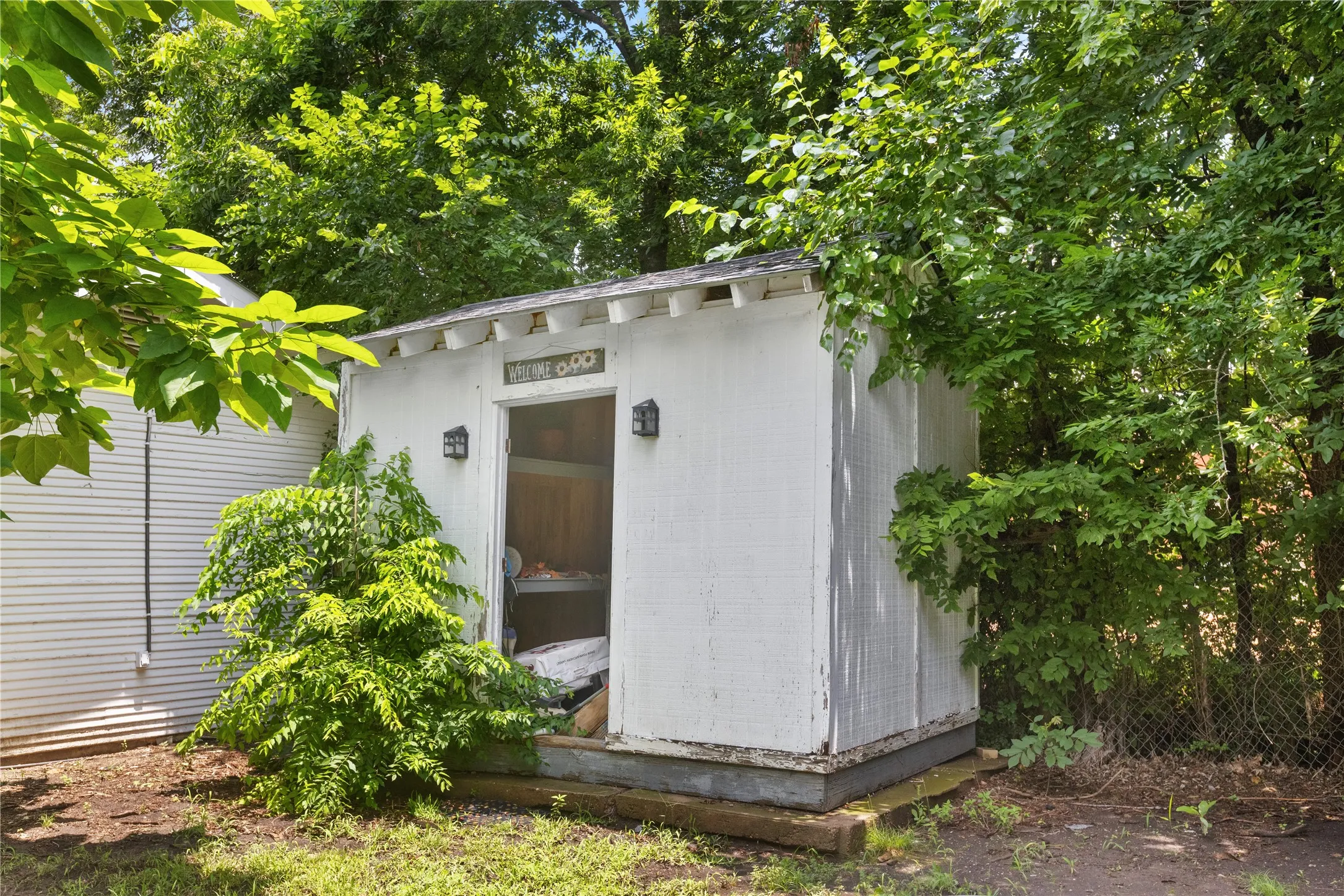 White storage shed featuring two exterior wall sconces and a solid wood door