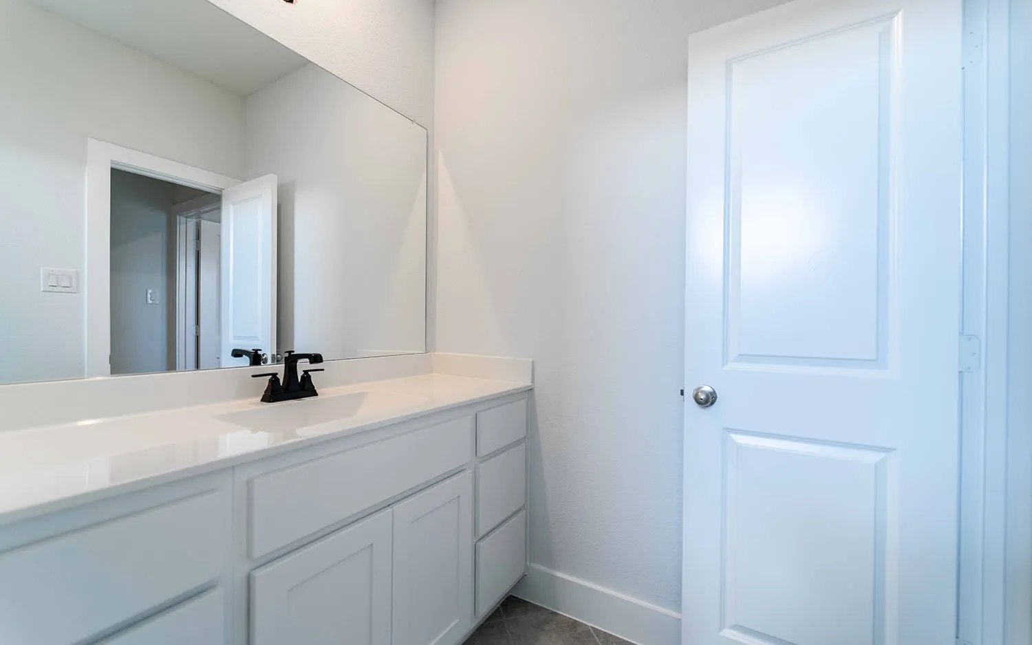 Vanity featuring a white countertop with an undermount sink and a matte black faucet