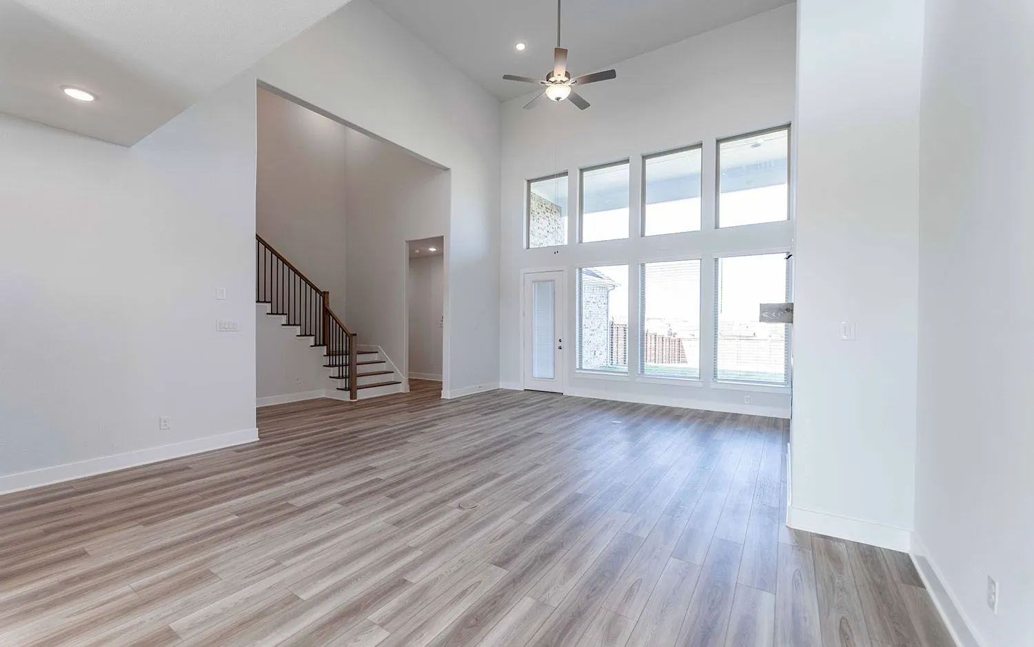 Two-story living area featuring wood-finish flooring and a high vaulted ceiling with a ceiling fan