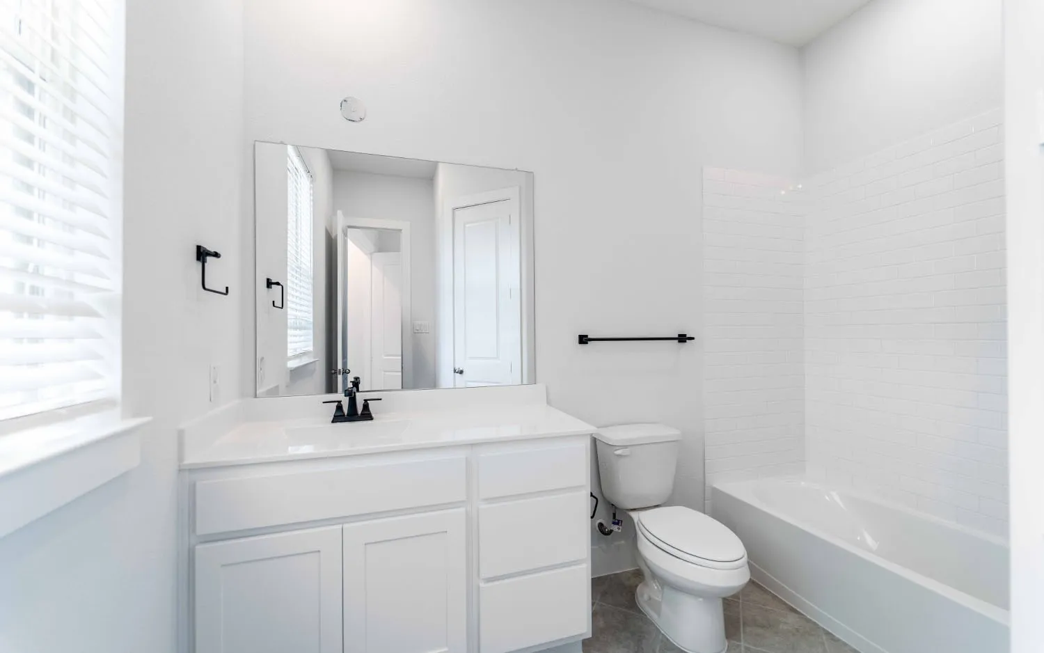 Bathroom featuring a single vanity with white cabinetry, a built-in rectangular sink, and a black-finish faucet