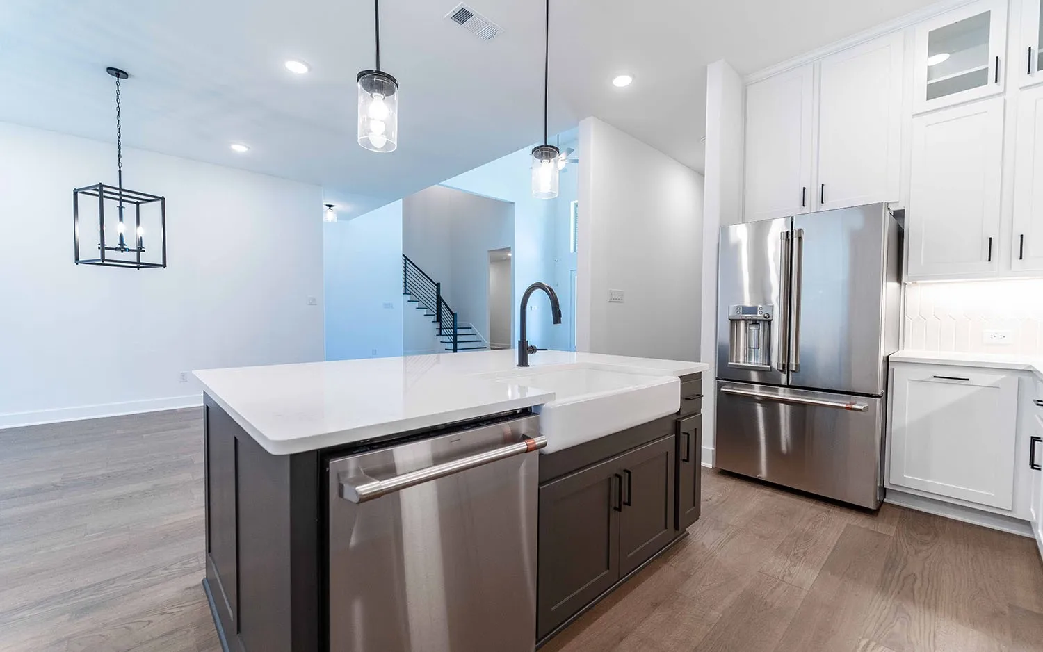 Gourmet kitchen featuring a central island with a farmhouse sink, white countertops, and stainless steel appliances