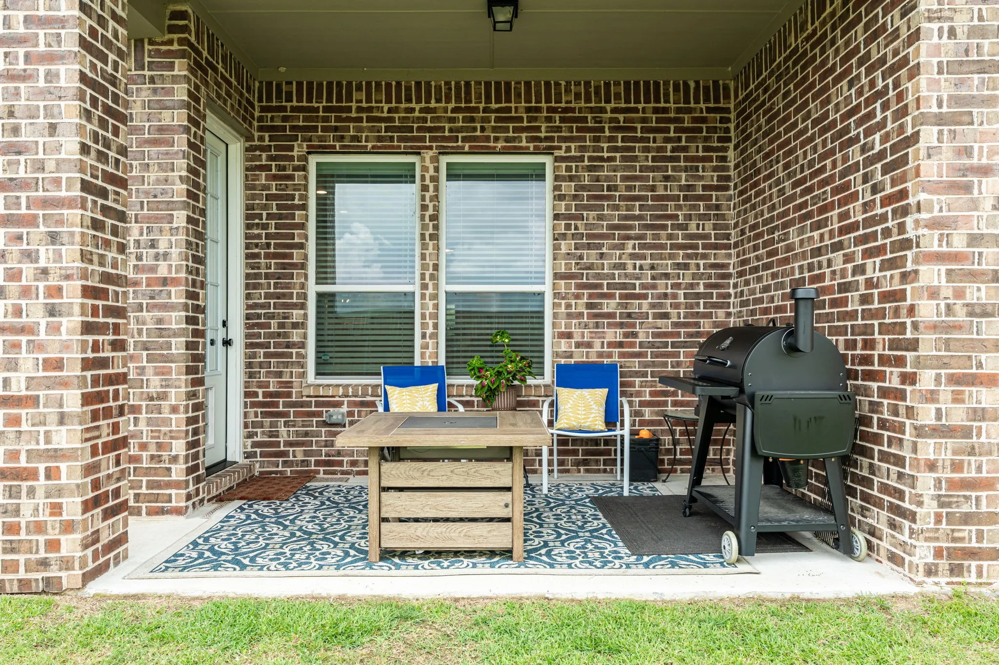 Covered patio featuring brick exterior walls, a concrete floor, and a white exterior door