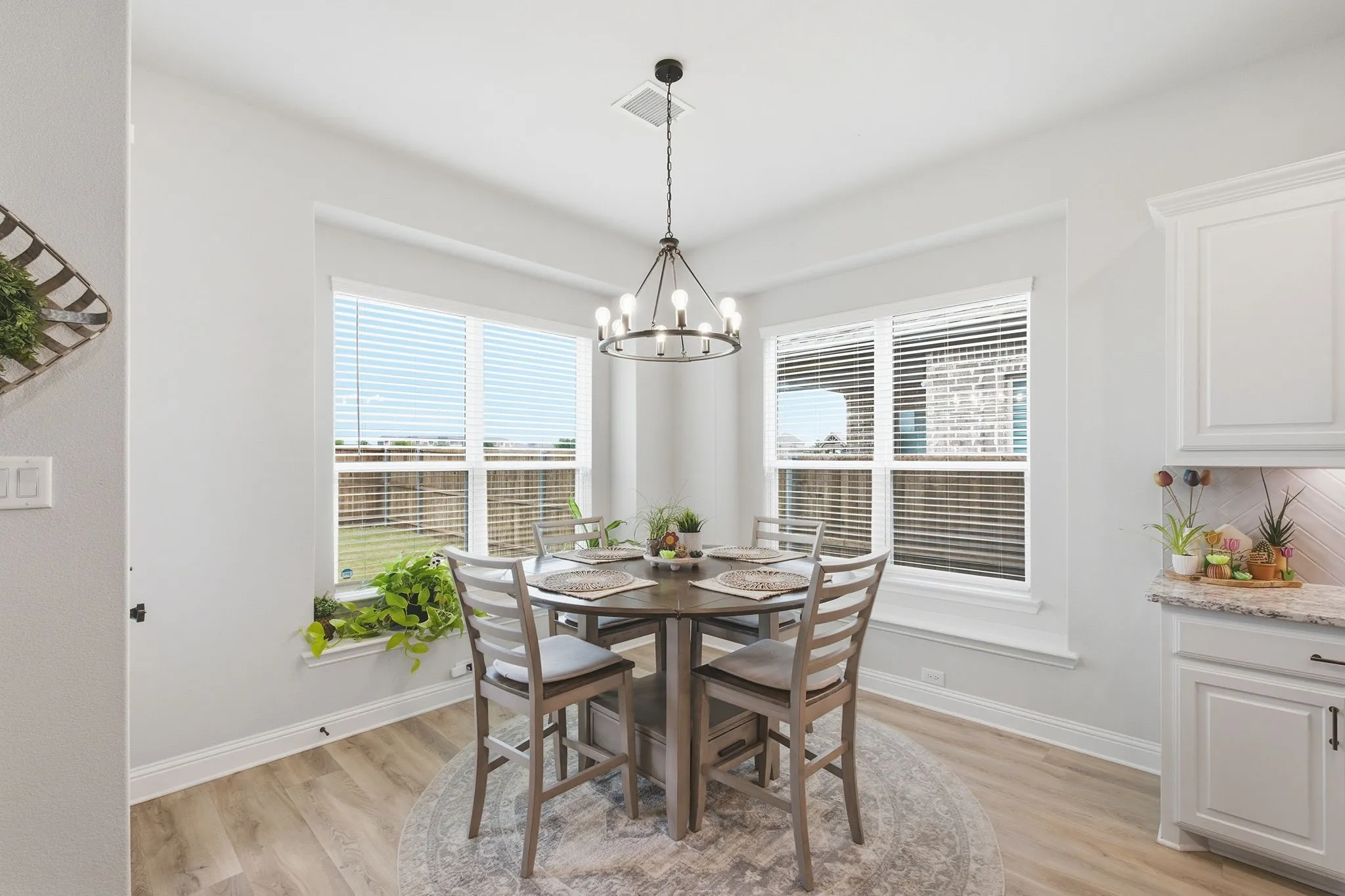 Dining area featuring wood-finish flooring, a contemporary chandelier, and multiple windows providing ample natural light