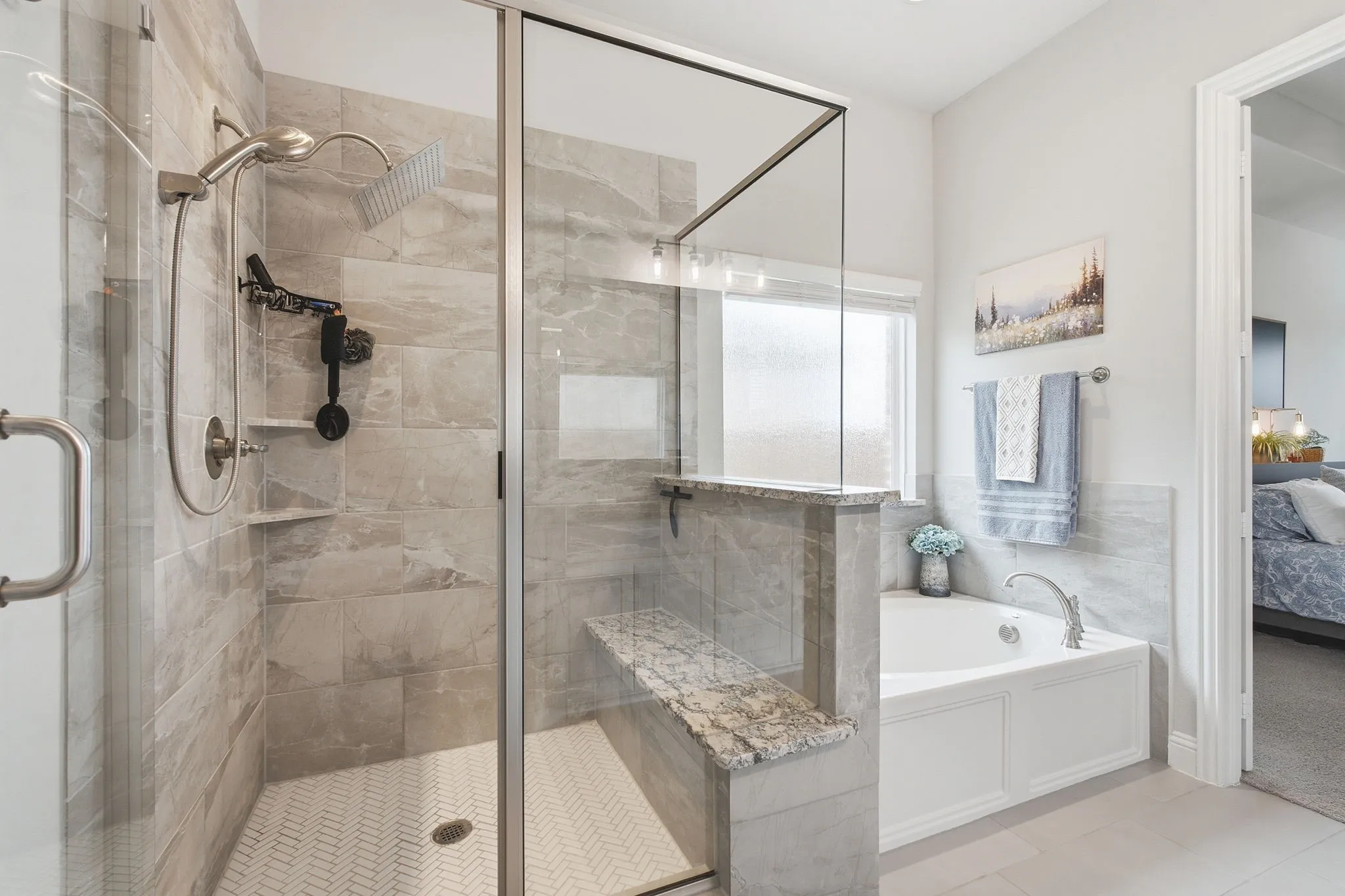 Walk-in shower with clear glass enclosure, large format tile walls, and a herringbone tile floor